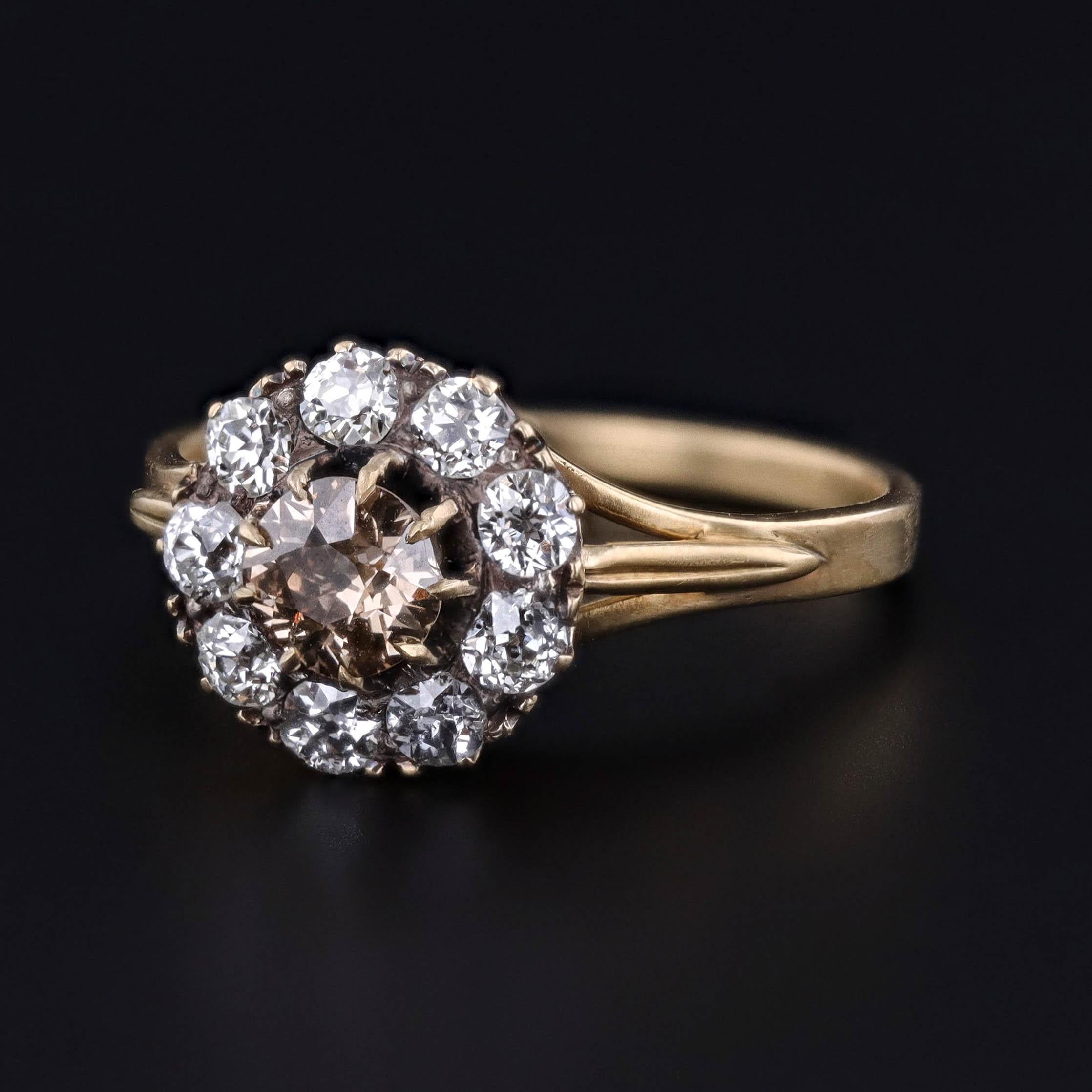 Bague ancienne à marguerite en diamant datant de 1910.  La bague en or 18 carats est ornée d'un diamant de taille européenne ancienne de 0,33 carat de couleur jaune orange clair, entouré d'un halo de neuf diamants de taille européenne ancienne.  Le