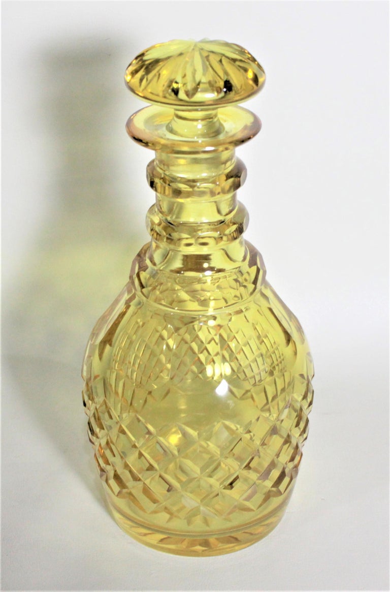 This antique yellow cut crystal liquor decanter most likely originates from England and made in circa 1900 in the Victorian style. The body of the decanter is cut in a diamond pattern and the neck has textured banded rings which function as grips.