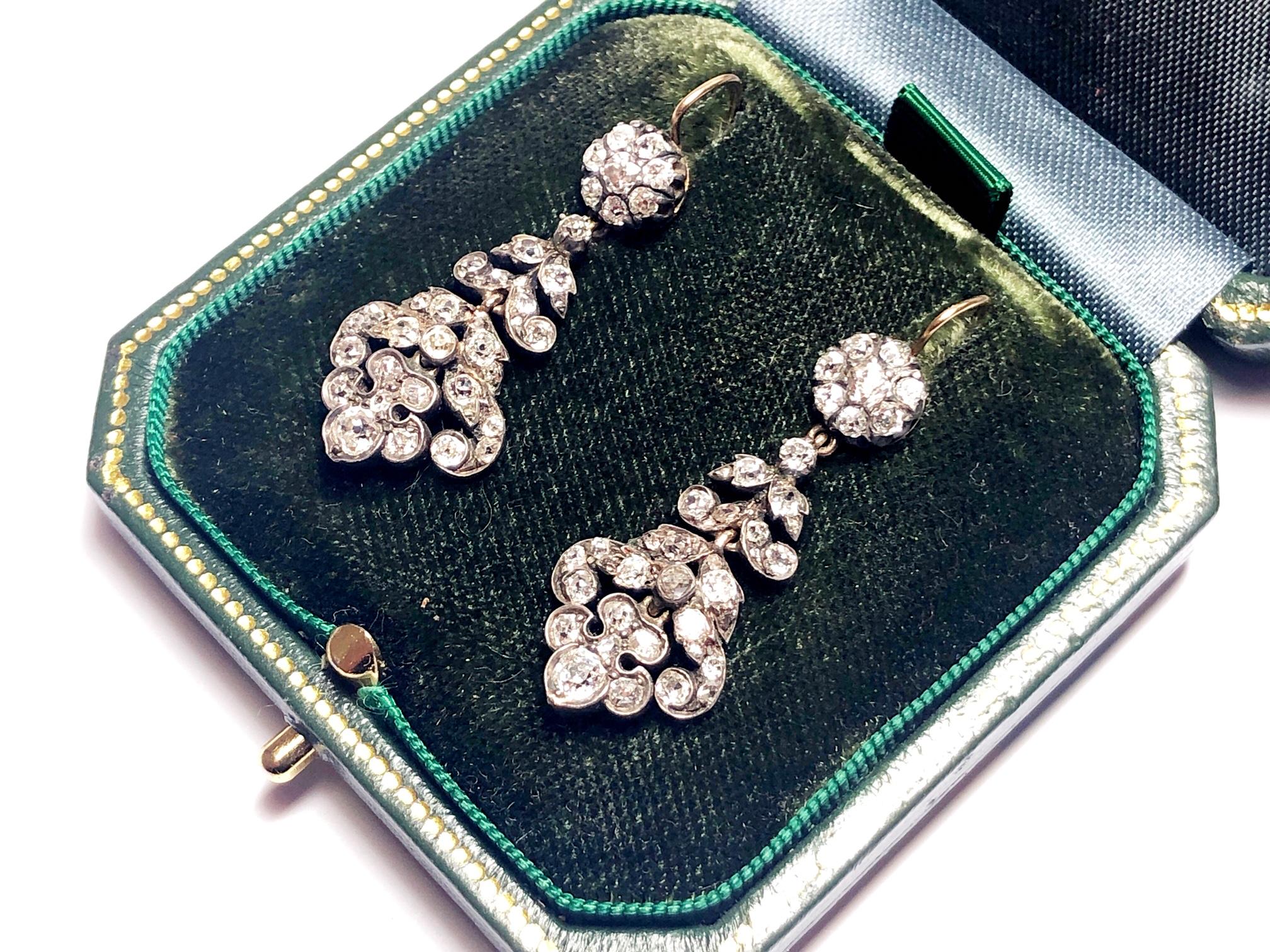 An antique pair of old-cut diamond earrings, with cluster tops and foliate drops, mounted in silver-upon-gold.