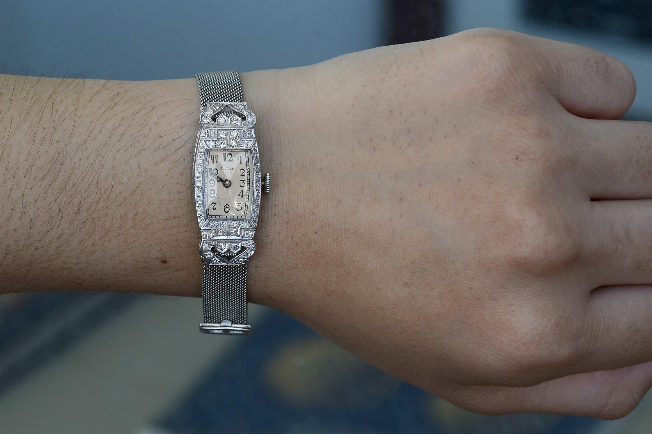 This stunning antique diamond Elgin 1920s Art Deco watch features a platinum & white gold case along with the dial's stylized numerals. The white gold mesh band is smooth, sleek and has an adjustable buckle to accommodate many wrist sizes. The face