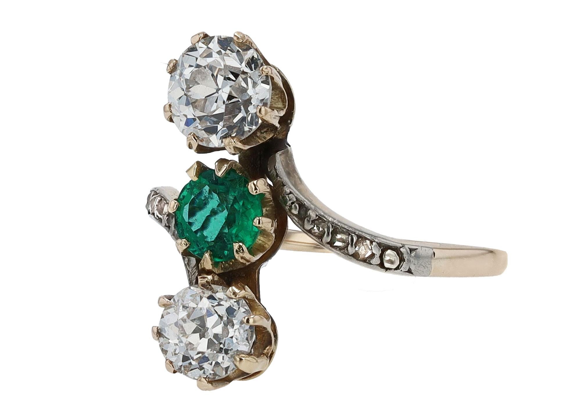 A mesmerizing trio of diamonds and an emerald form this fabulous 3 stone antique Edwardian engagement ring. The vertical orientation maximizes your finger length along with a dramatic, sinuous silhouette showcasing  a duet of old European cut