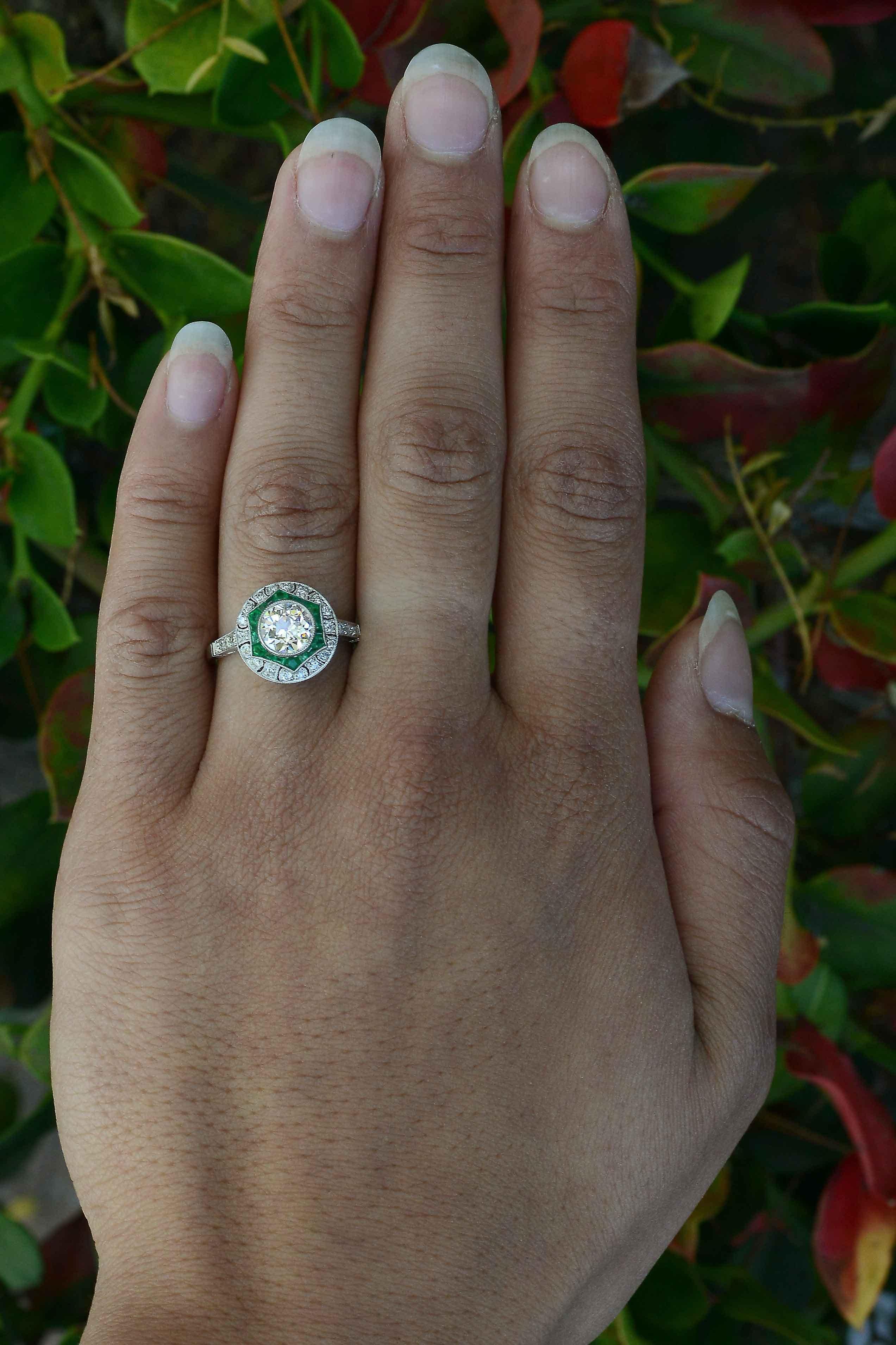 An Antique Diamond and Emerald Engagement Ring inspired by the Art Deco period, the intriguing star design fashioned as a crown dome is centered by a juicy 1.13 carat, 100 year old mine cut brilliant diamond. The large, chunky facets, display a