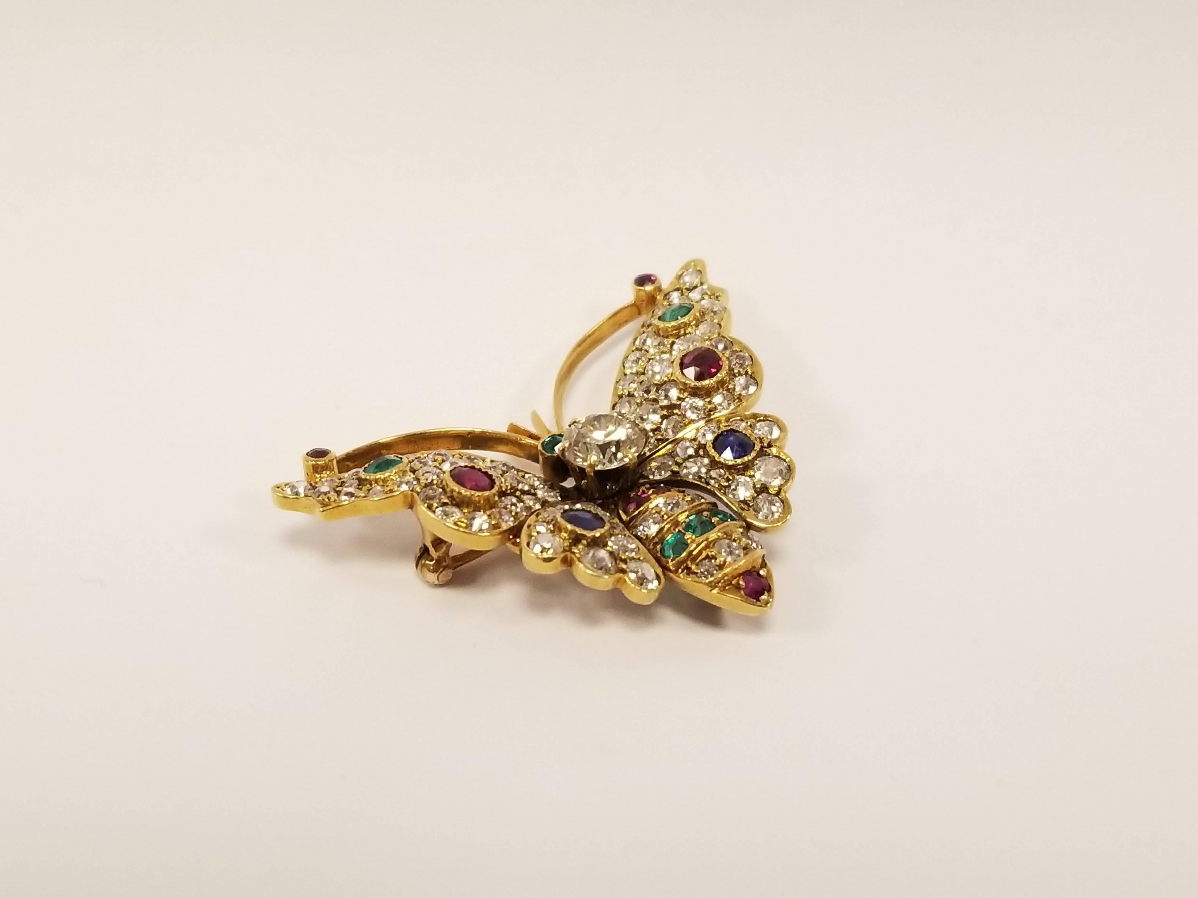 An Antique 18 karat gold butterfly brooch with diamonds,  emeralds, rubies and sapphires. The dimensional butterfly brooch centers on an old European-cut diamond with an approximate weight of 1.00 carat. The brooch has an additional 82 Old