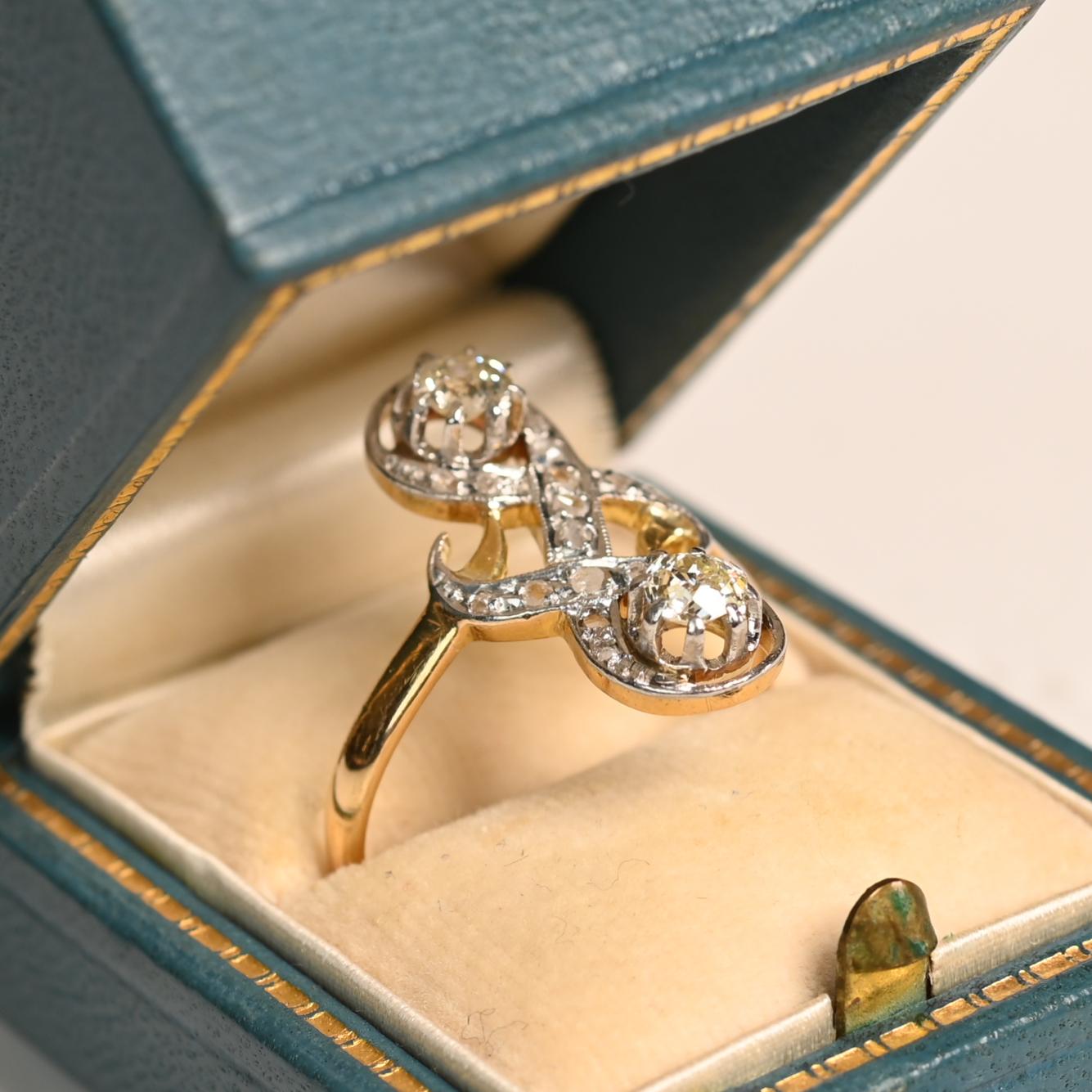 Questo squisito anello antico edoardiano a due pietre mette in mostra una coppia di affascinanti diamanti di taglio europeo antico, con un peso complessivo di circa 0,5 carati. Classificati come colore K e purezza SI1, questi diamanti mostrano il
