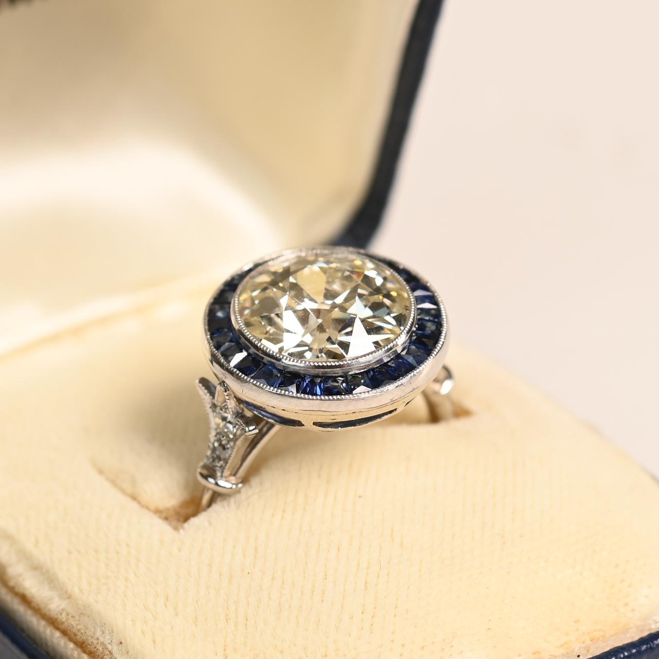 Dieser exquisite Ring präsentiert in seiner Mitte einen atemberaubenden Diamanten im alten europäischen Schliff von ca. 4,20 Karat, der zeitlose Schönheit und Vintage-Charme ausstrahlt. Der Diamant ist von einem auffälligen Halo aus sorgfältig
