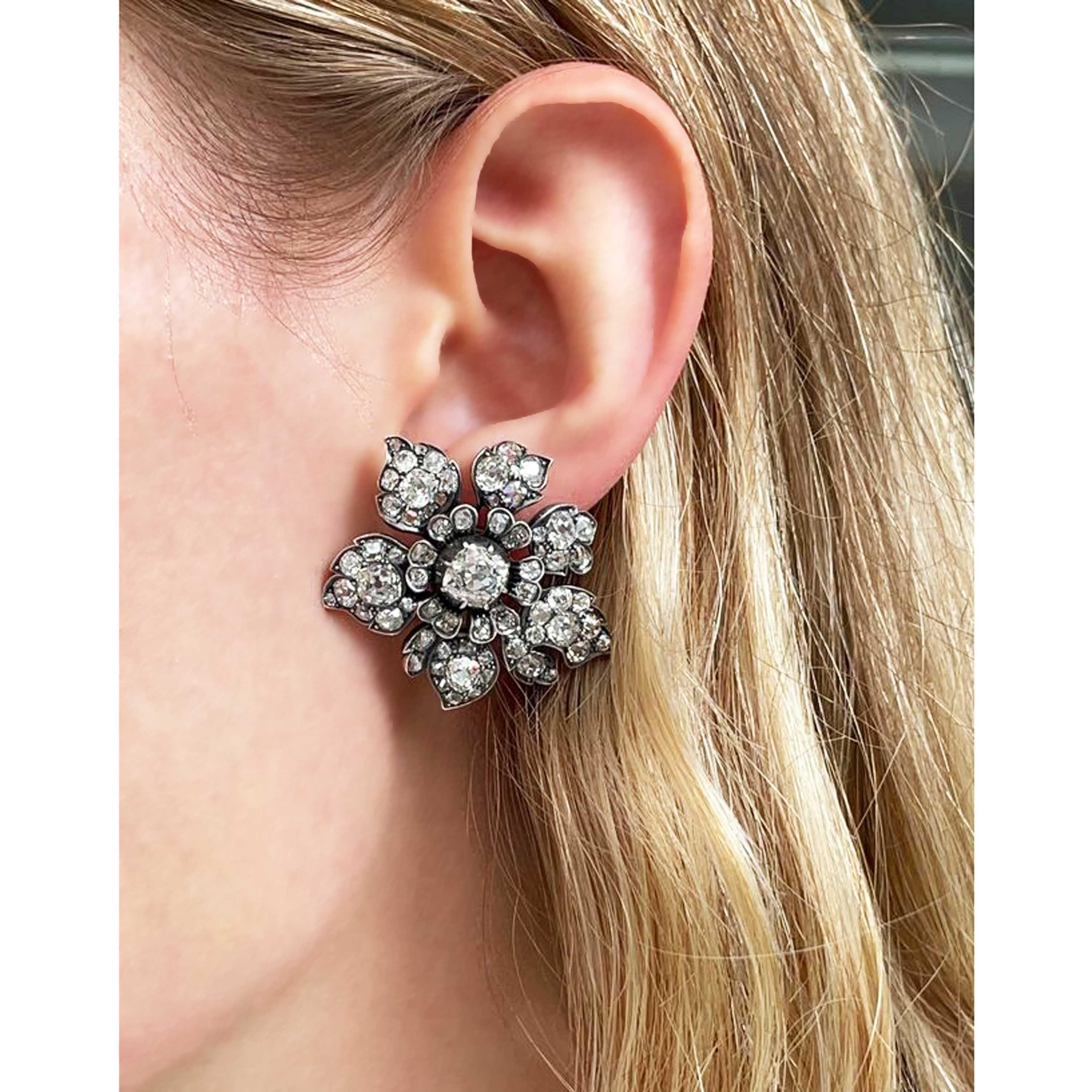 A pair of antique diamond flower earrings, set with approximately 9.00ct of old-cut diamonds, in total, with the principle cushion shaped diamond weighing approximately 1.50ct, in each, in cut down settings, with a surround of old-cut diamonds, in