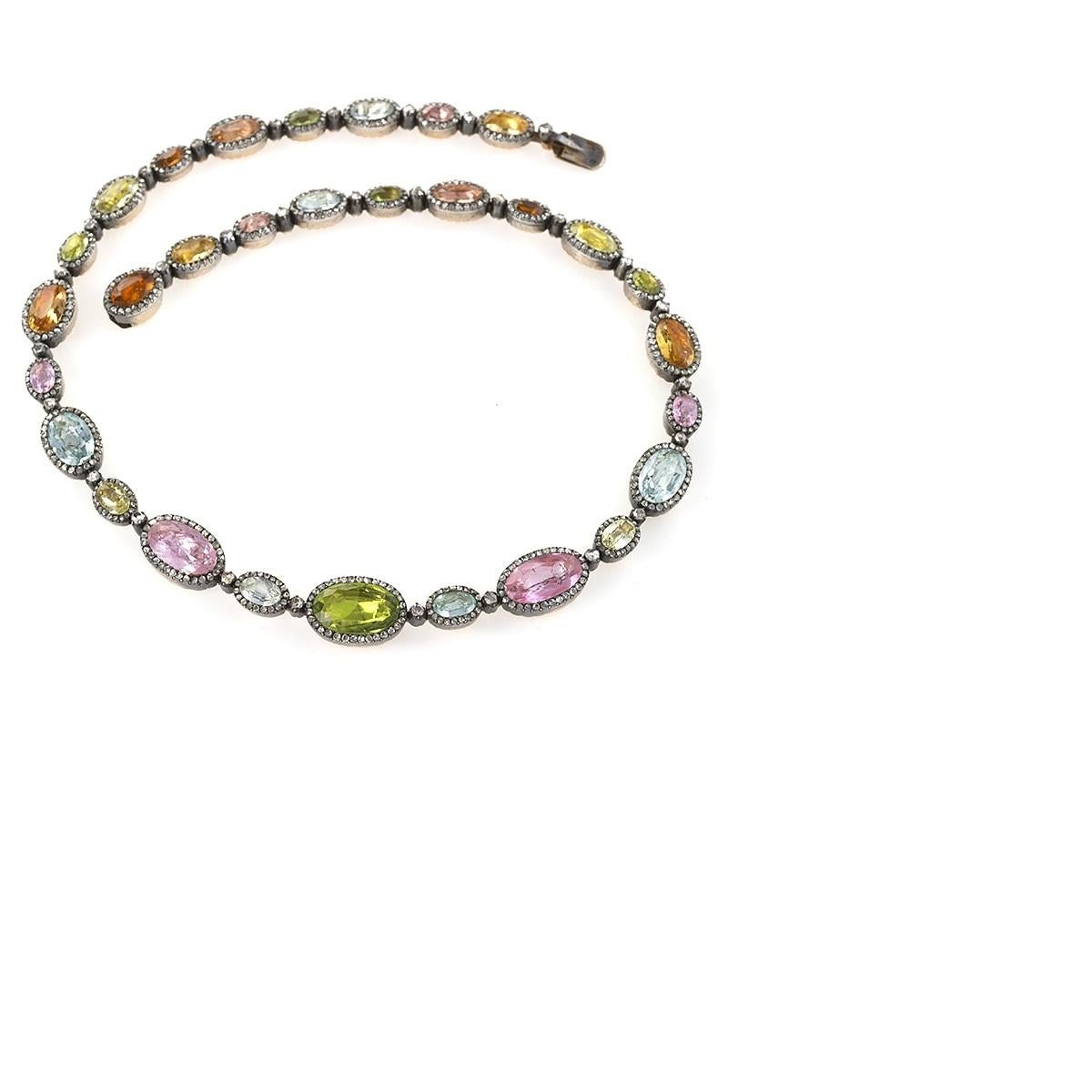 A French Antique 18 karat gold and silver top necklace with diamonds, peridots, grossularite garnets, pink topaz, aquamarines and chrysoberyls. The graduated, foiled colored stones are framed and spaced with rose-cut diamonds weighing approximately