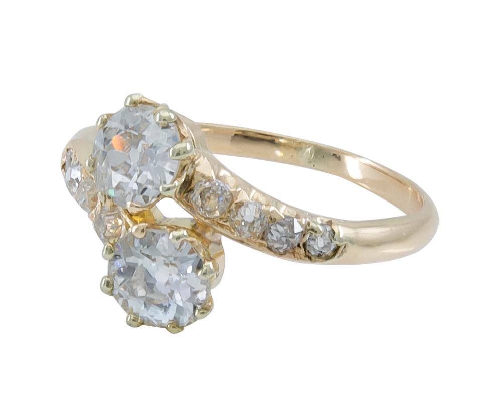 Antique Toi et Moi ring.  The main stones are old-mine cut diamonds in individual prong settings, approximately  .90 carats each.  Set with four old-mine cut  diamonds on each side. Exceptionally fiery and lively stones.   Beautiful handmade 14K