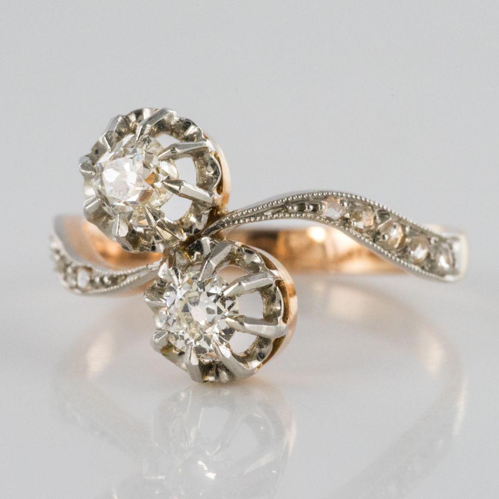 Ring in 18 carat rose gold and platinum. 
This delicate Lovers Ring represents femininity incarnate. It is claw set with an antique brilliant cut round diamond and a cushion cut diamond. 
On each side the beginning of the ring band, in the form of a