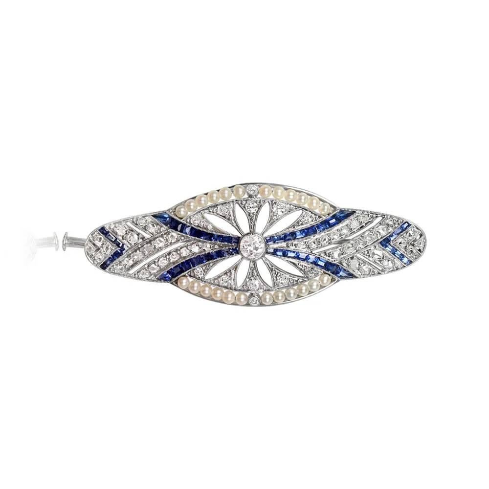 Exquisite Art Deco era brooch featuring an old European cut diamond center stone (approximately 0.17 carats), accented by floral openwork set with single cut diamonds. Rows of natural sapphires and rose-cut diamonds create a captivating design,