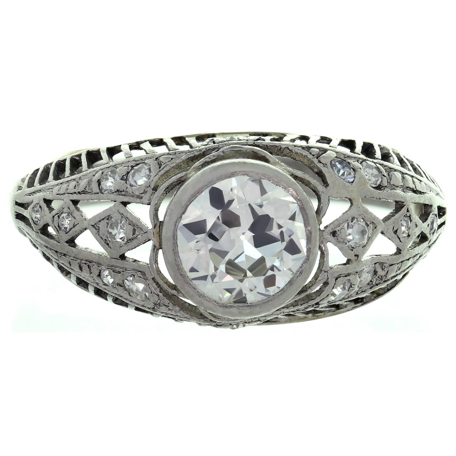 This splendid antique engagement ring features a classic filigree design crafted in platinum and accented with a sparkling European-cut VS clarity H-I color central diamond of an estimated 0.72-0.75, surrounded with 16 single-cut diamonds of an