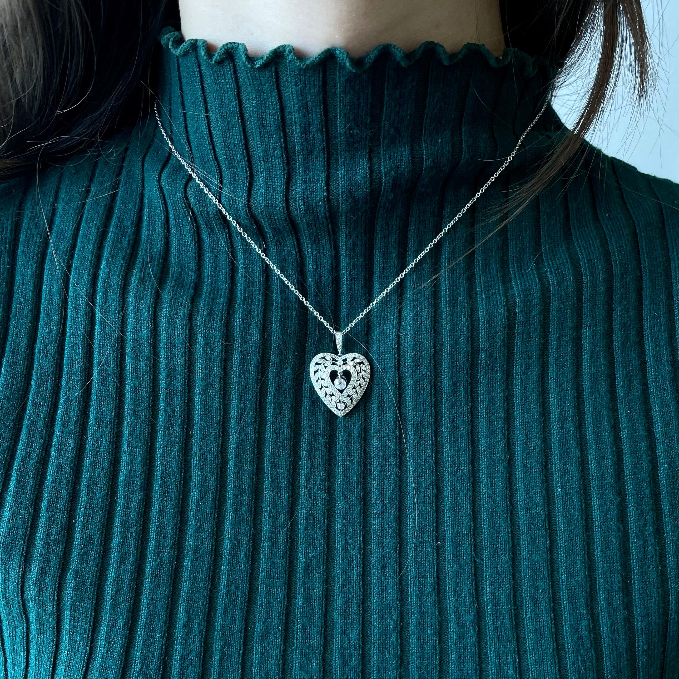 Antique Diamond Platinum Heart Pendant. The pendant features an Old European Cut diamond, approximately 0.20 carat, G color, SI clarity. Accented by 96 Round Brilliant Cut diamonds approximately 1.00 carat. Modern chain. Circa 1910's. 16