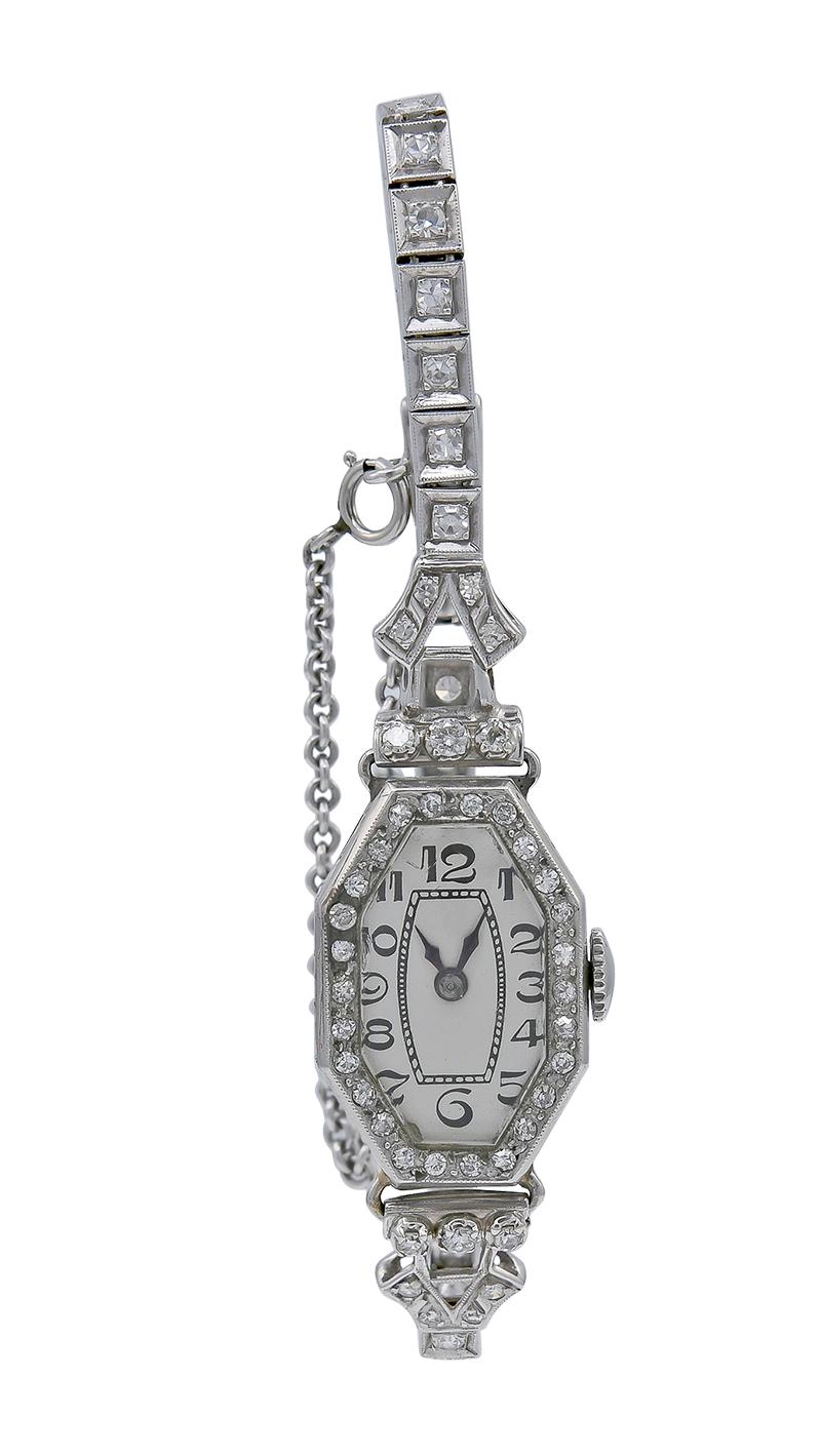 Elegant antique women's watch with a lovely elongated octagonal shape.  Platinum, with diamonds circling the face, the connectors and the bracelet.  Enamel letters.  Safety chain.  6 1/2