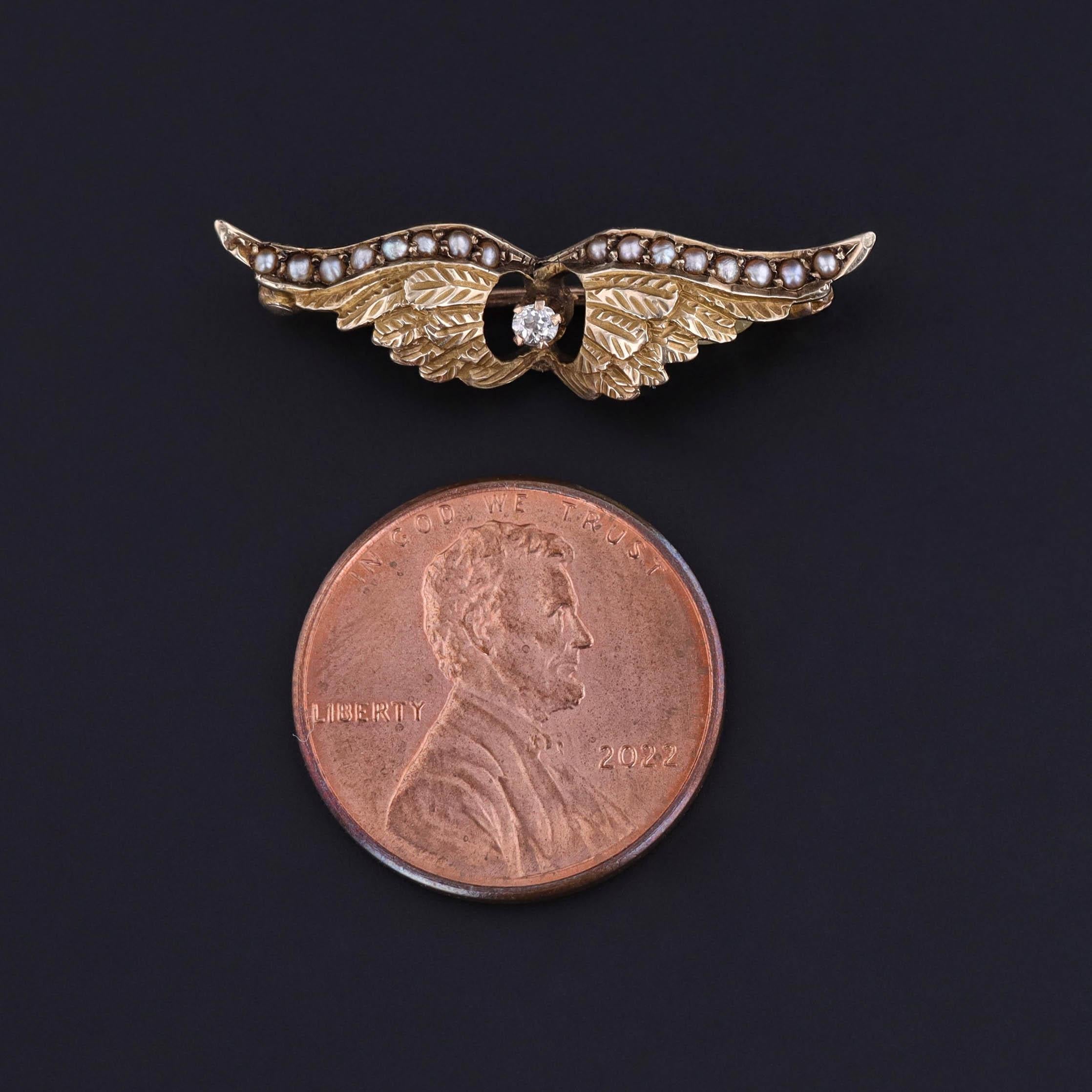 An antique brooch dates to 1900 and features a pair of wings of 10k gold, studded with pearls and accented with a prong set diamond.

The piece measures 0.3 inches by 1.1 inches wide and weighs 1.44 grams. It is in great condition.

The metal