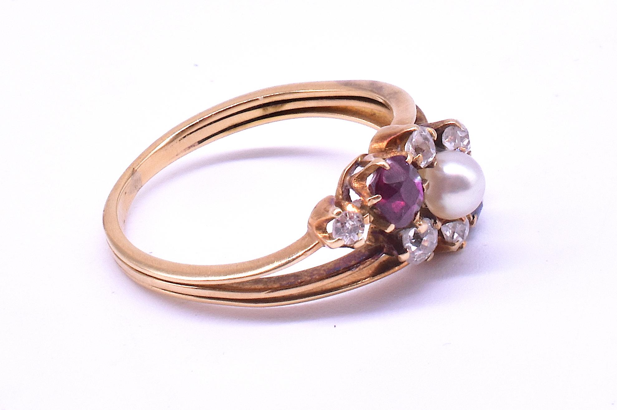 Dieser antike 15-karätige Diamant-, Saphir-, Rubin- und Perlenring aus der Zeit um 1910 gefällt uns wegen seiner starken Kombination von Formen und Farben sowie seiner dynamischen Symmetrie. Der Ring ist diagonal angeordnet, im Gegensatz zu der