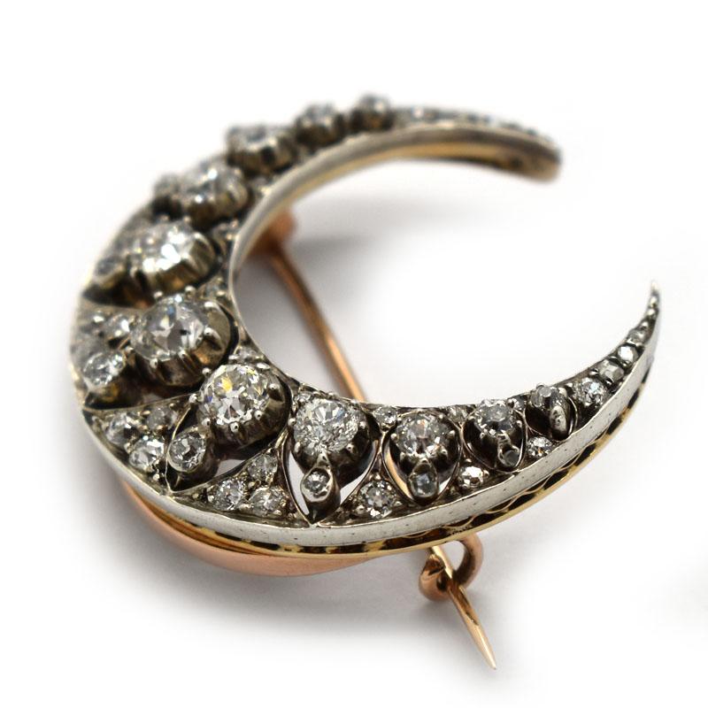 An antique diamond crescent brooch, set with old-cut diamonds, mounted in silver-upon-gold, with a row of diamonds in the inner crescent, in cut down settings, with a row of smaller diamonds, in rub over settings, spaced with triangles of pavé set