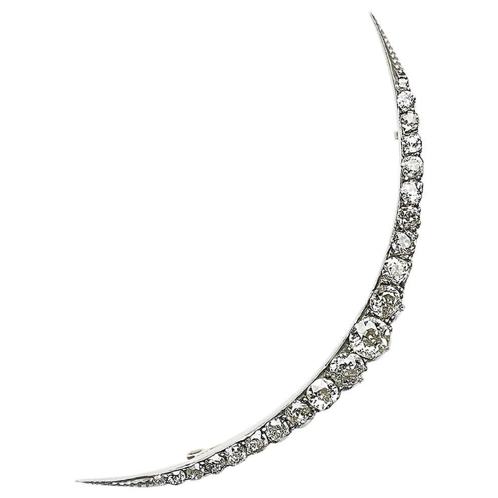 An antique diamond crescent brooch, set with approximately 2.00ct of graduating old-cut diamonds, mounted in silver-upon-gold, with a plain inner curve and cut down set outer curve, with gold gallery work below. Circa 1890.
In Victorian symbolism