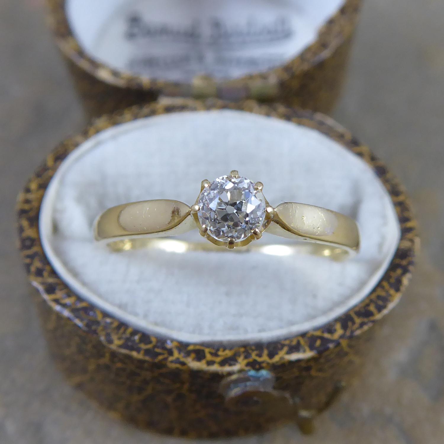 An antique ring set with an old cut diamond approx.  0.23ct  claw set in yellow gold to raised and pointed shoulders to a D-shaped, cross-sectioned gold band hallmarked 18ct yellow gold  at the Birmingham Assay Office for the year 1899.  A perfectly