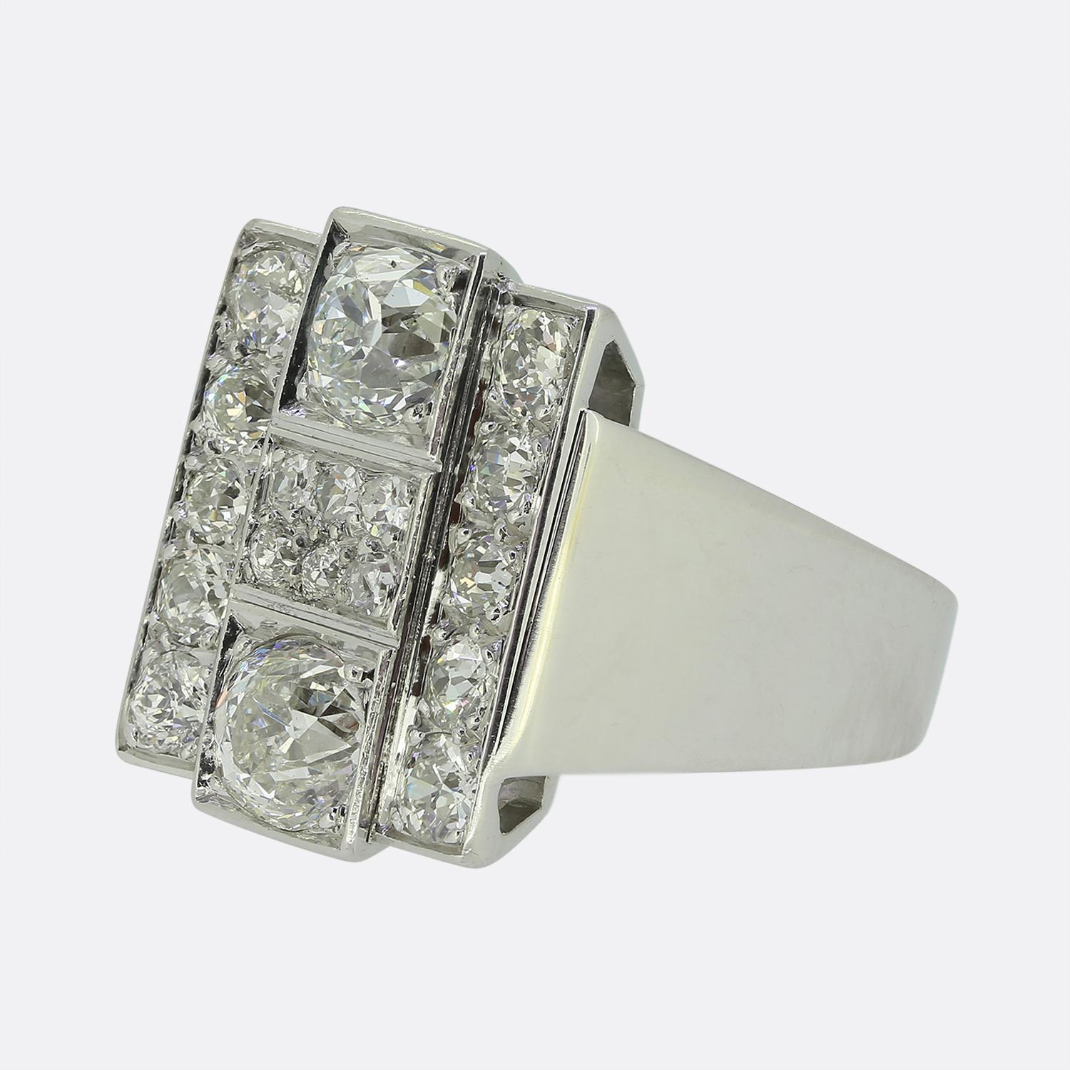 Aquí tenemos un llamativo anillo de pastilla que exhibe un cautivador racimo de diamantes redondos facetados de talla antigua. Esta disposición focal de piedras ofrece un radiante blanco brillante; todas ellas están contenidas dentro de cenefas de