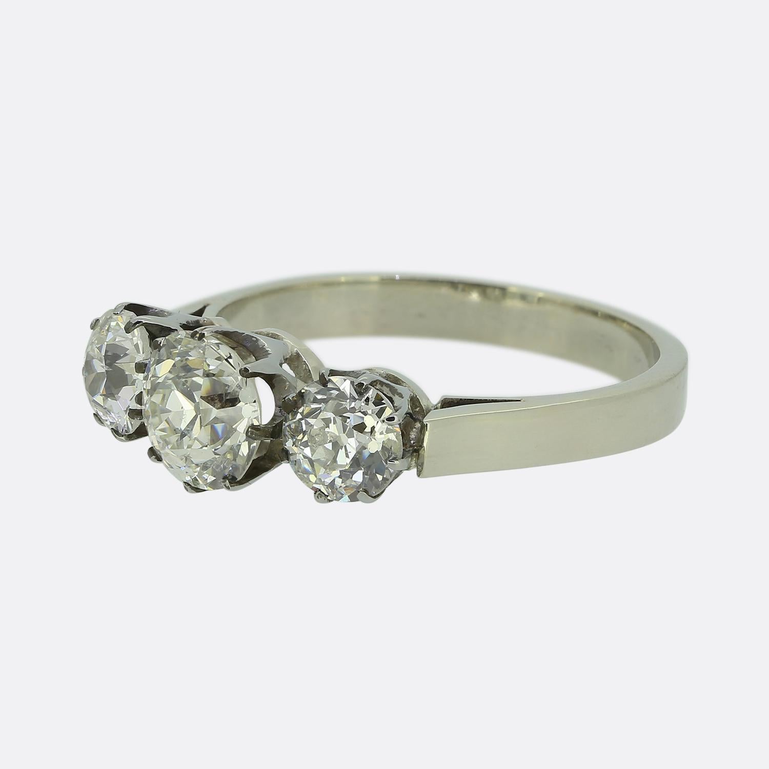 Nous avons ici une délicieuse bague à trois pierres. Réalisée en or blanc 18 ct, cette pièce présente un trio de diamants ronds facettés de taille ancienne. Le diamant central est flanqué de deux pierres plus petites assorties, toutes d'un éclat