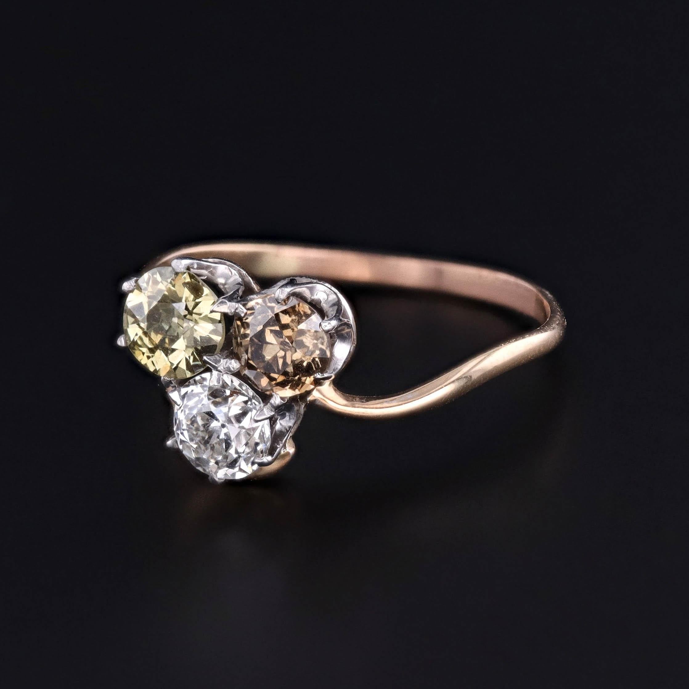 Dieser antike Ring im Kleeblattformat aus dem Jahr 1920 weist drei natürliche Diamanten im alten europäischen Schliff auf, die mit Zacken aus Weißgold auf einem Band aus 14 Karat Gelbgold gefasst sind. Die farblosen, gelben und braunen