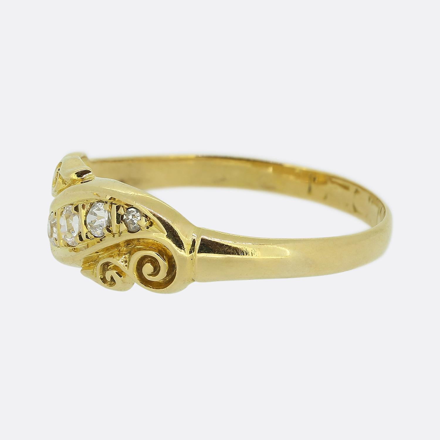 Here we have a delightful twist ring dating back to the Victorian period. This antique piece showcases five round faceted old cut diamonds in a diagonal formation which graduate in size towards the centre. An ornate scrolled design at either side of