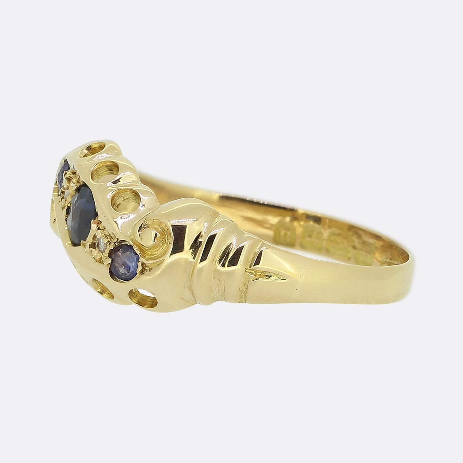 Here we have a delightful three-stone twist ring dating back to the early stages of the 20th century. This 18ct antique piece showcases three round faceted navy blue sapphires in a diagonal formation across the face with a duo of rose cut diamonds