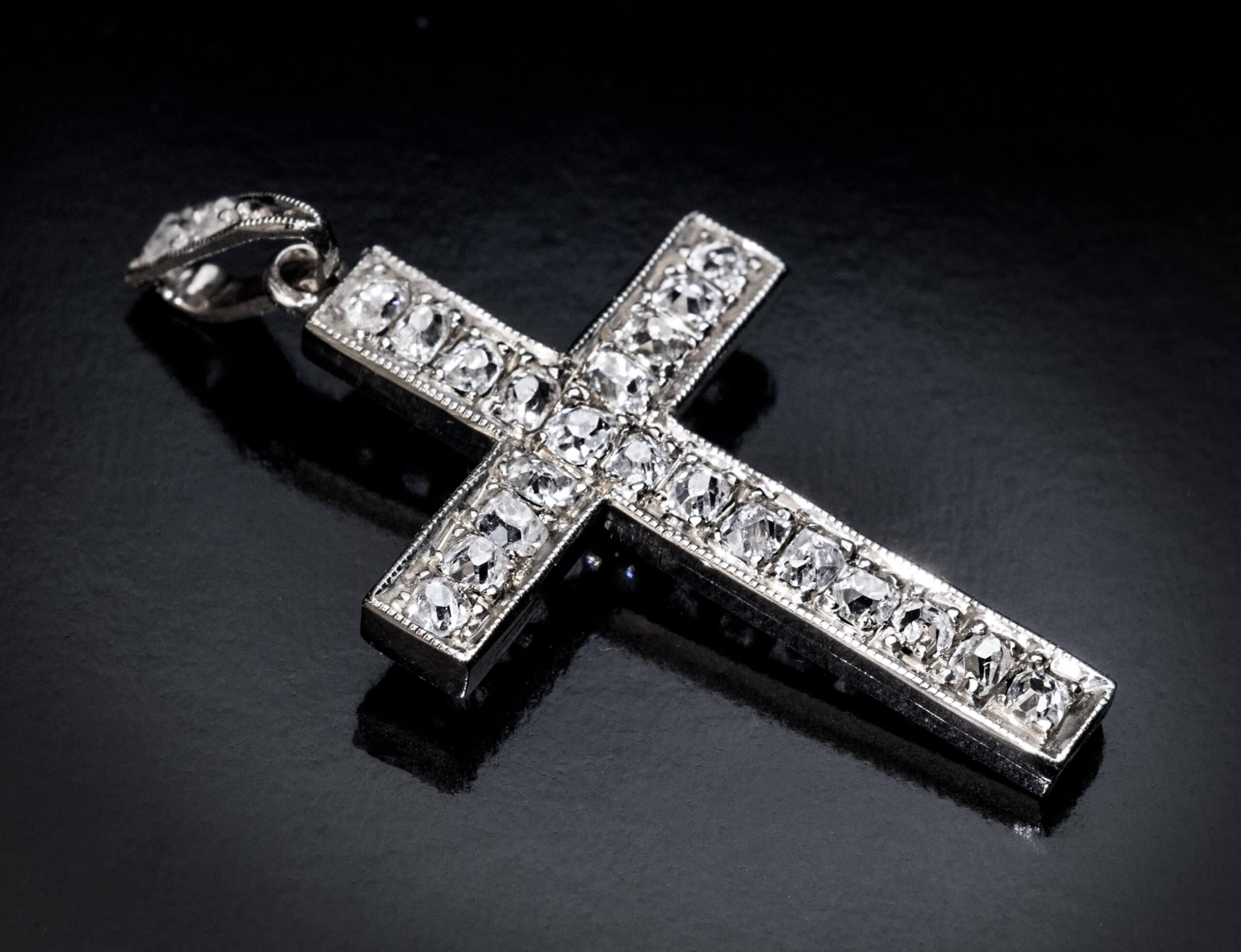 1920s  Il pendente a croce in oro bianco 14K è impreziosito da grossi diamanti antichi taglio cuscino. A giudicare dal taglio, i diamanti sono del XIX secolo o precedenti.  La croce è contrassegnata sulla cauzione con il marchio d'importazione