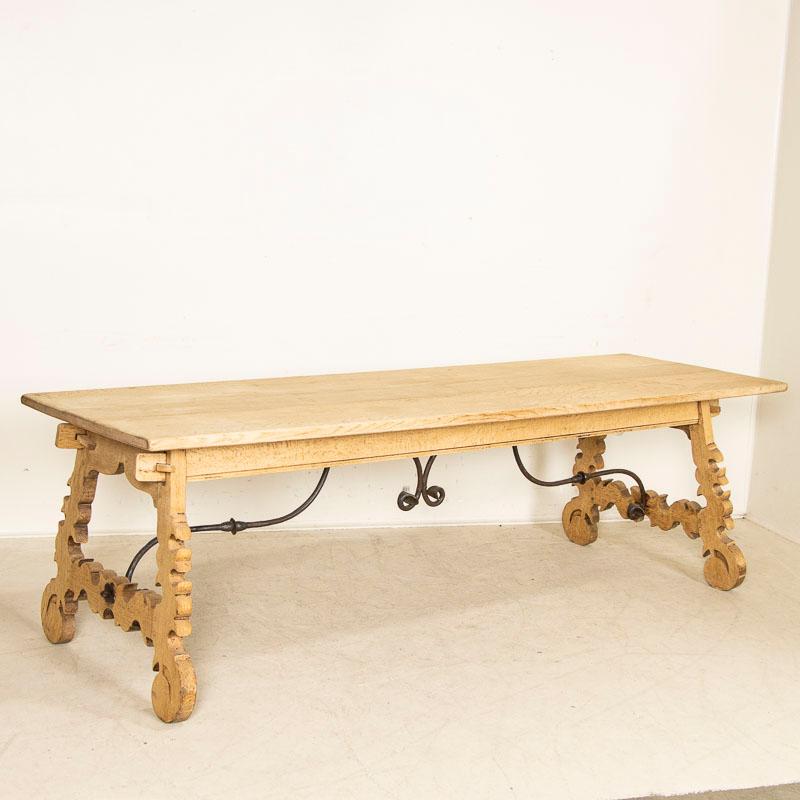 This fascinating 8' table holds visual intrigue due to the decorative carved harp shaped wood legs. Notice the intriguing carved details of the legs supported by the wrought iron scroll work of the unique base. The top is comprised of 3 planks.