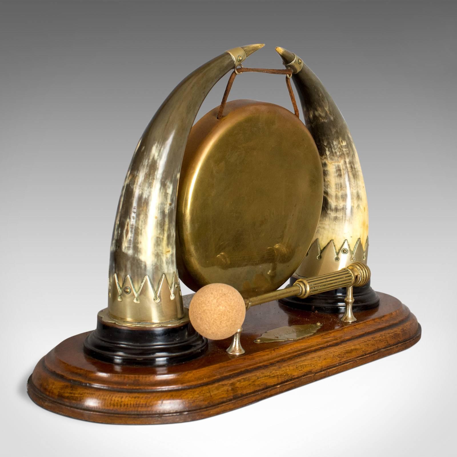 This is an antique dinner gong, an English, Edwardian table gong hung from cow horns on an oak plinth, circa 1910. 

Magnificent antique table dinner gong
Bronze gong hung on leather straps from silvered mounts
Attractive polished cow horn