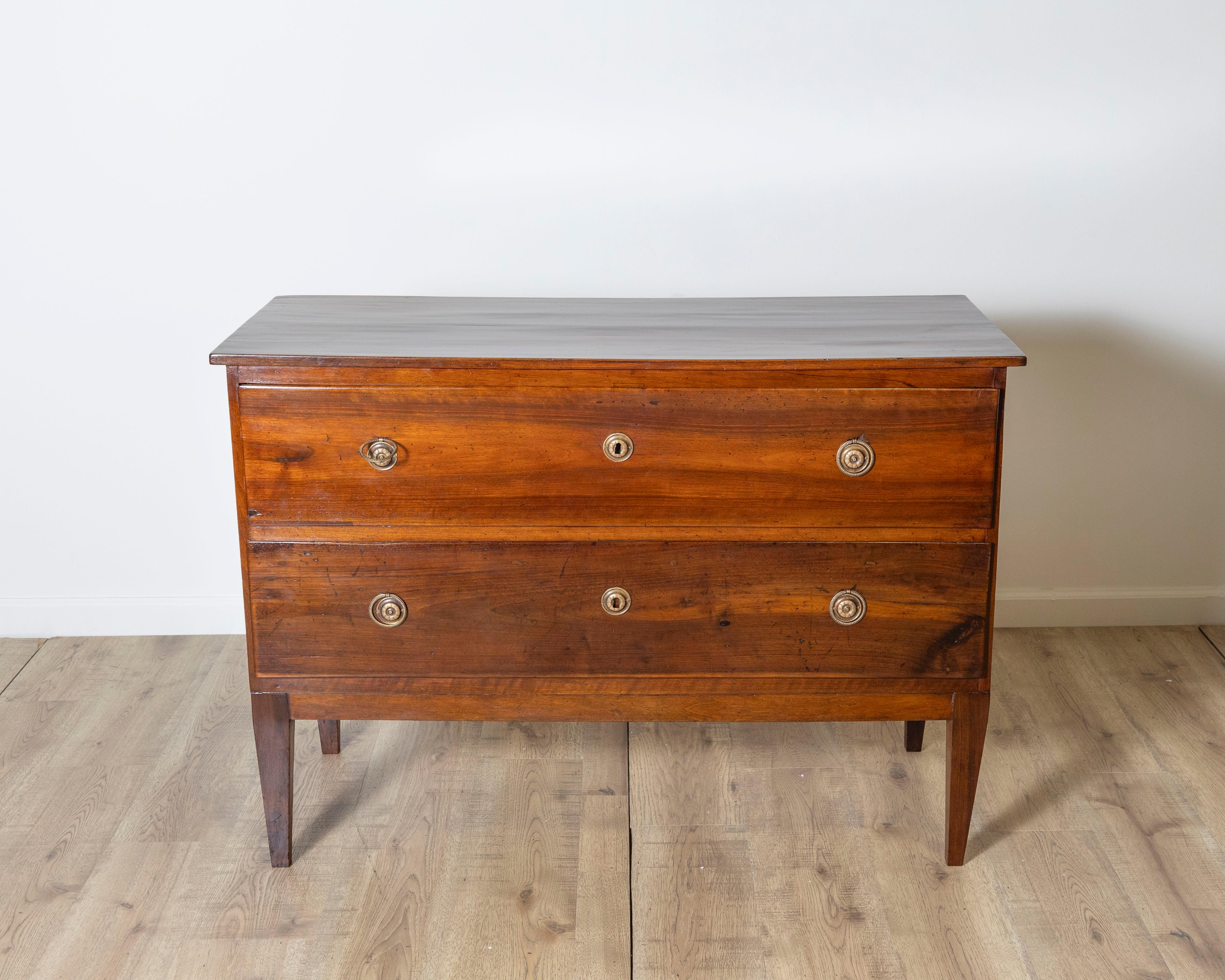 Cette élégante commode Directoire est originaire de Modène, dans la région d'Elega, en Italie, et date de la fin du XVIIIe siècle. Entièrement réalisée en noyer massif, cette pièce est une belle représentation du style néoclassique raffiné qui