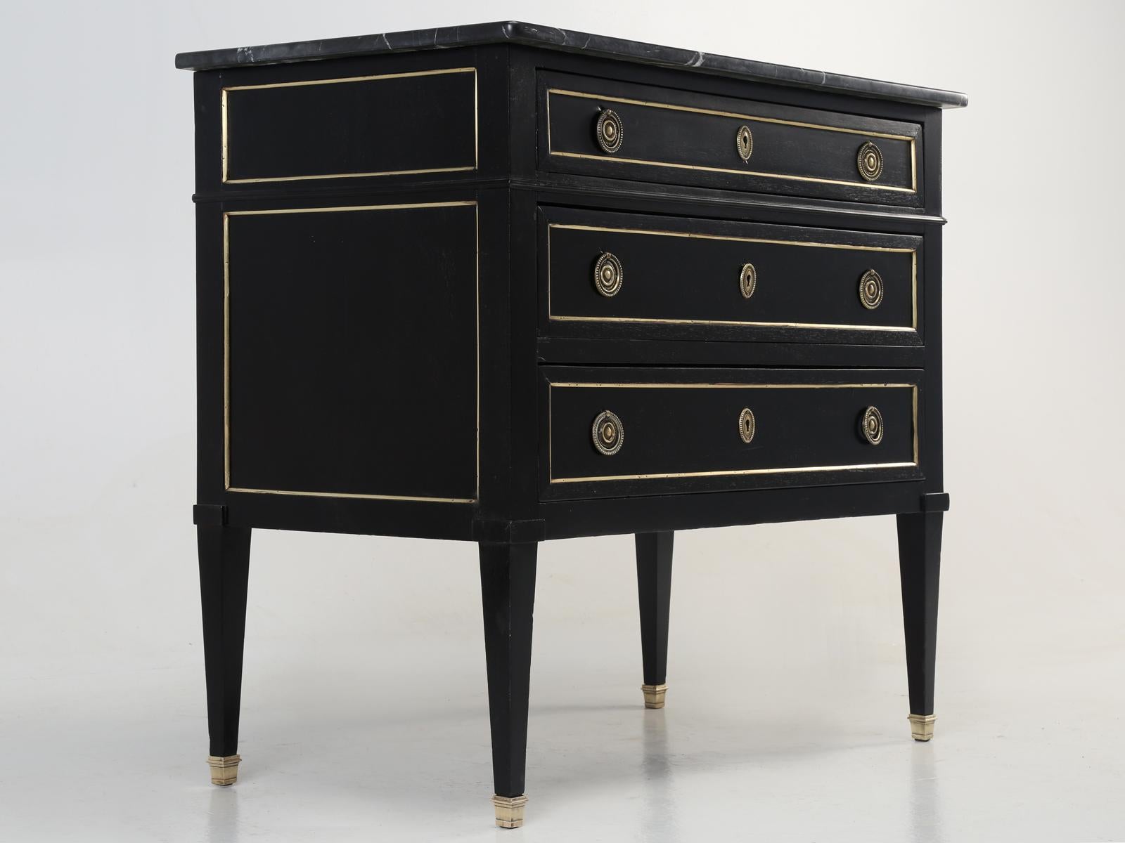 Antique French Directoire commode from the mid-1800s. Our Old Plank finishing department hand-scrapped the entire antique French petite commode, without the use of any chemicals and applied an authentic ebonized finish. The marble top is free from