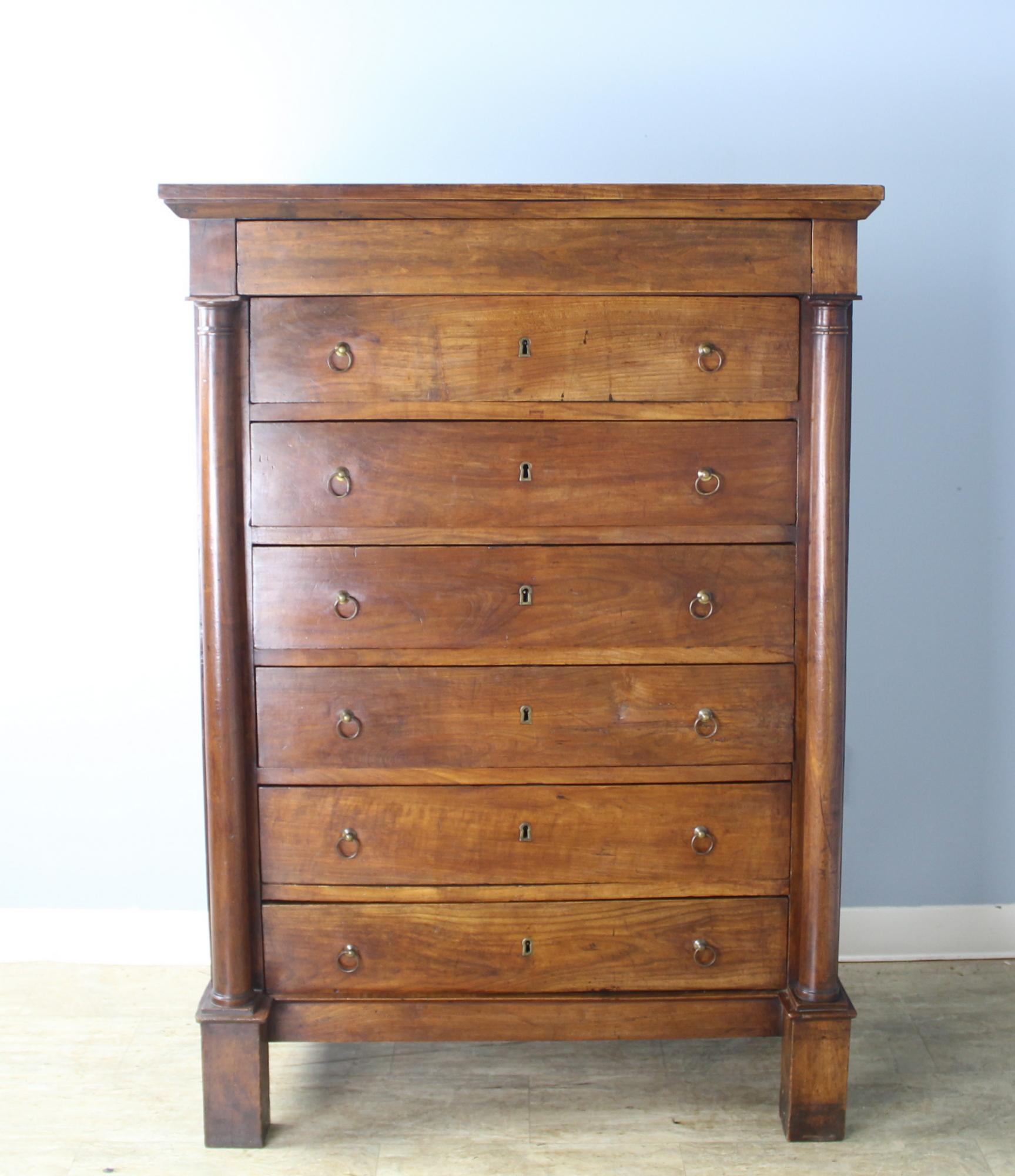 A handsome French cherry wood dresser with seven drawers, one for each day of the week. Nice Directoire column detail and block feet. The top has some small marks of distress, but the piece is in over all very good antique condition.