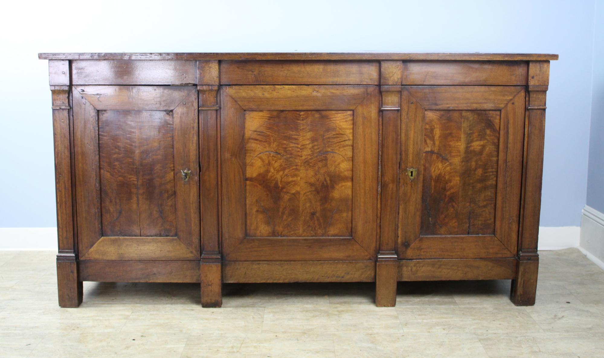 A striking walnut three-door enfilade from France's Directoire period. Beautifully and dramatically grained wood and an imposing silhouette. Both the single and double doored sides open to a wide, deep cupboard with a single shelf. Nicely mitered