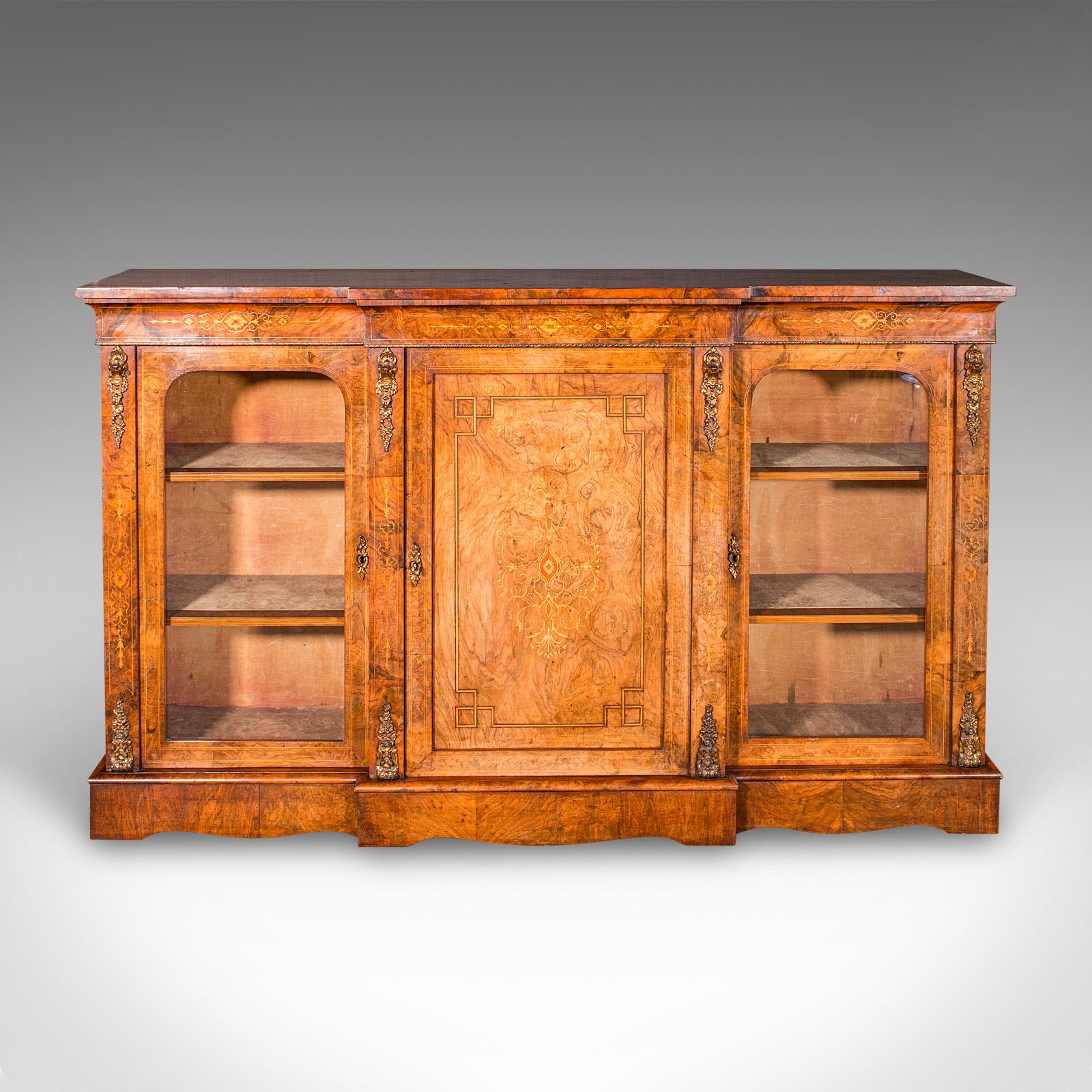 This is a large antique display bookcase, an English walnut breakfront library cabinet dating to the Regency period, circa 1820. 

A piece of superb Regency craftsmanship, boasting striking colour, refined detail and wonderful proportion
Traditional