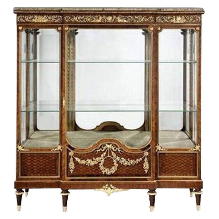 Napoleon III antique display cabinet.
This beautiful breakfront kingwood display cabinet has a central wide door flanked by two glazed panels enclosing a mirrored interior. It is surmounted by a wide frieze beneath a marble top. Set on six turned