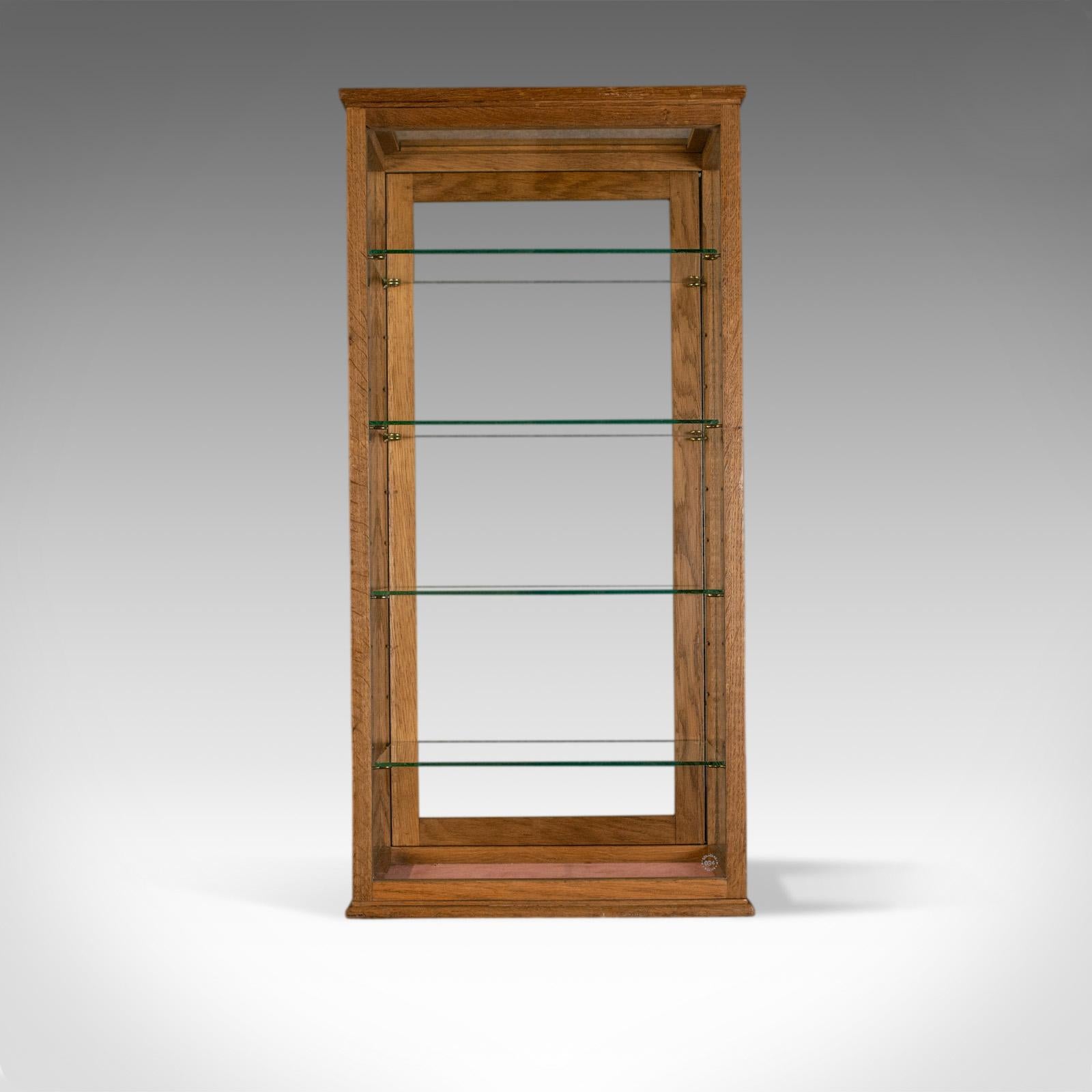 This is an antique counter display cabinet with four glass shelves. An English, late 19th century oak cabinet, circa 1900.

Crafted from oak and displaying plentiful grain interest
A desirable aged patina present throughout
Plate glass in good