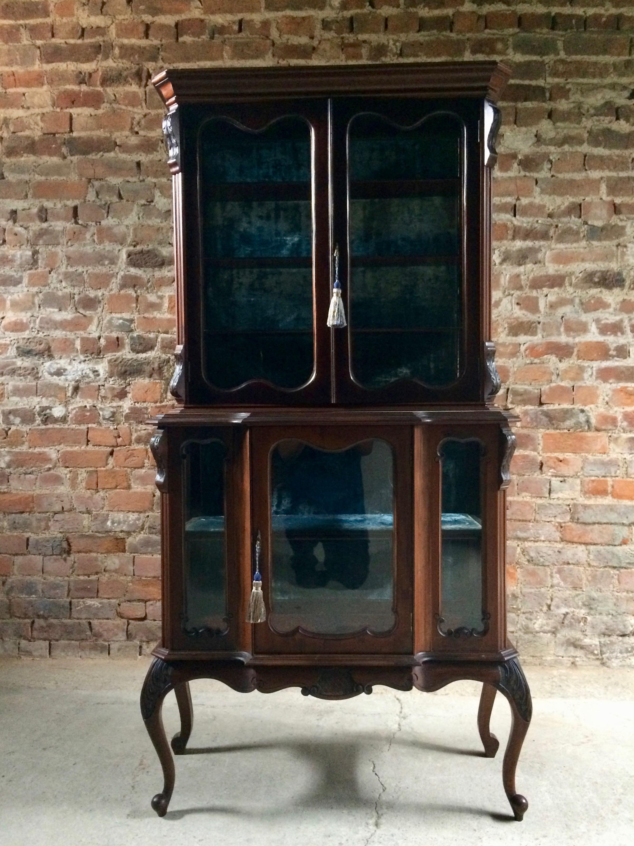 A late Victorian mahogany display cabinet, circa 1890, the top with molded cornice above a pair of glazed doors enclosing plush lined shelves flanked by canted angles and with glazed sides, the base with breakfront above a central door flanked by