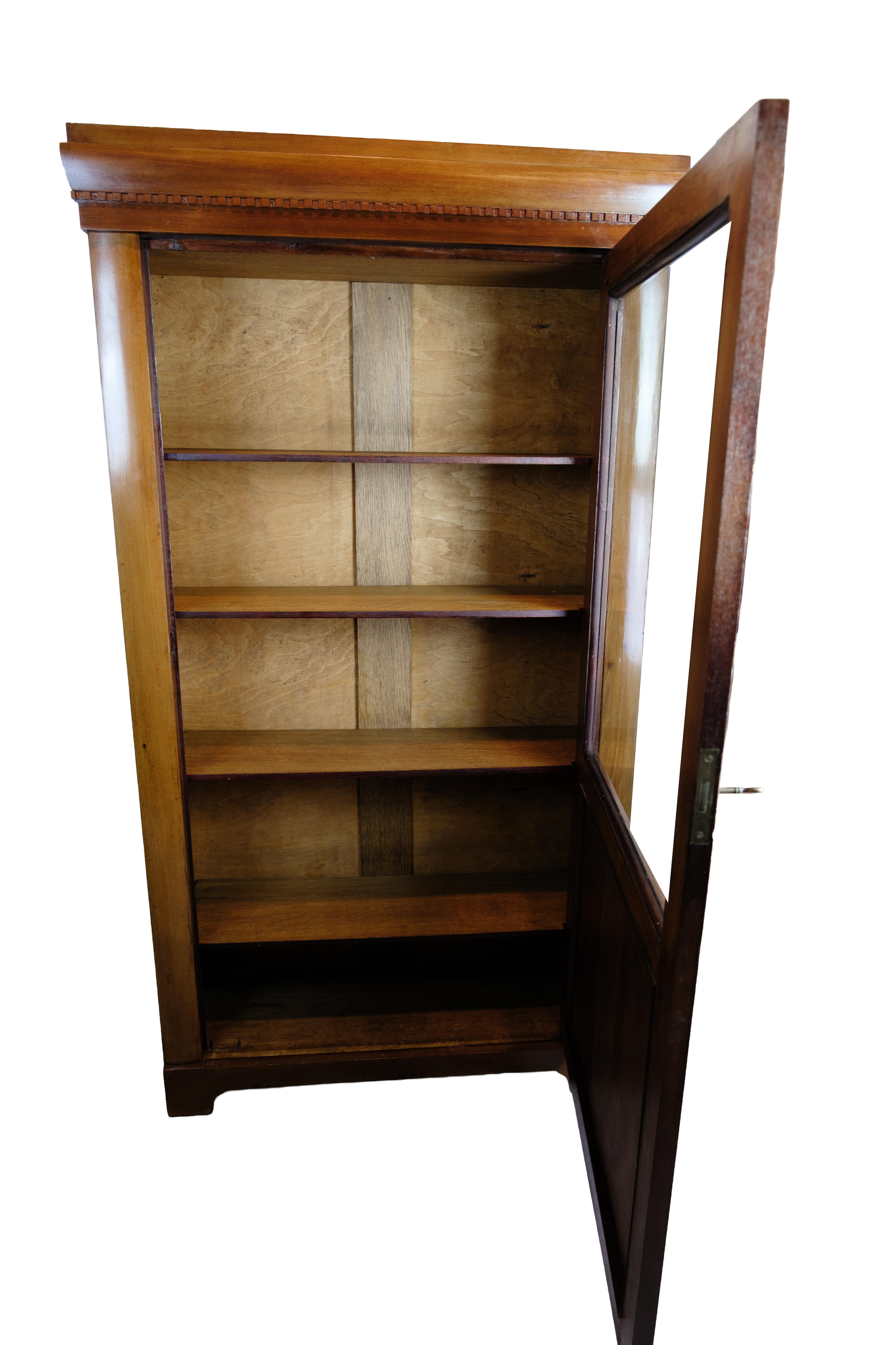 Vitrina de los años 20 de caoba con una sola puerta de cristal y cinco estantes regulables.

El armario tiene una tapa clásica con tallas y una buena profundidad, lo que lo hace adecuado para guardar tanto libros como porcelana. La puerta de cristal
