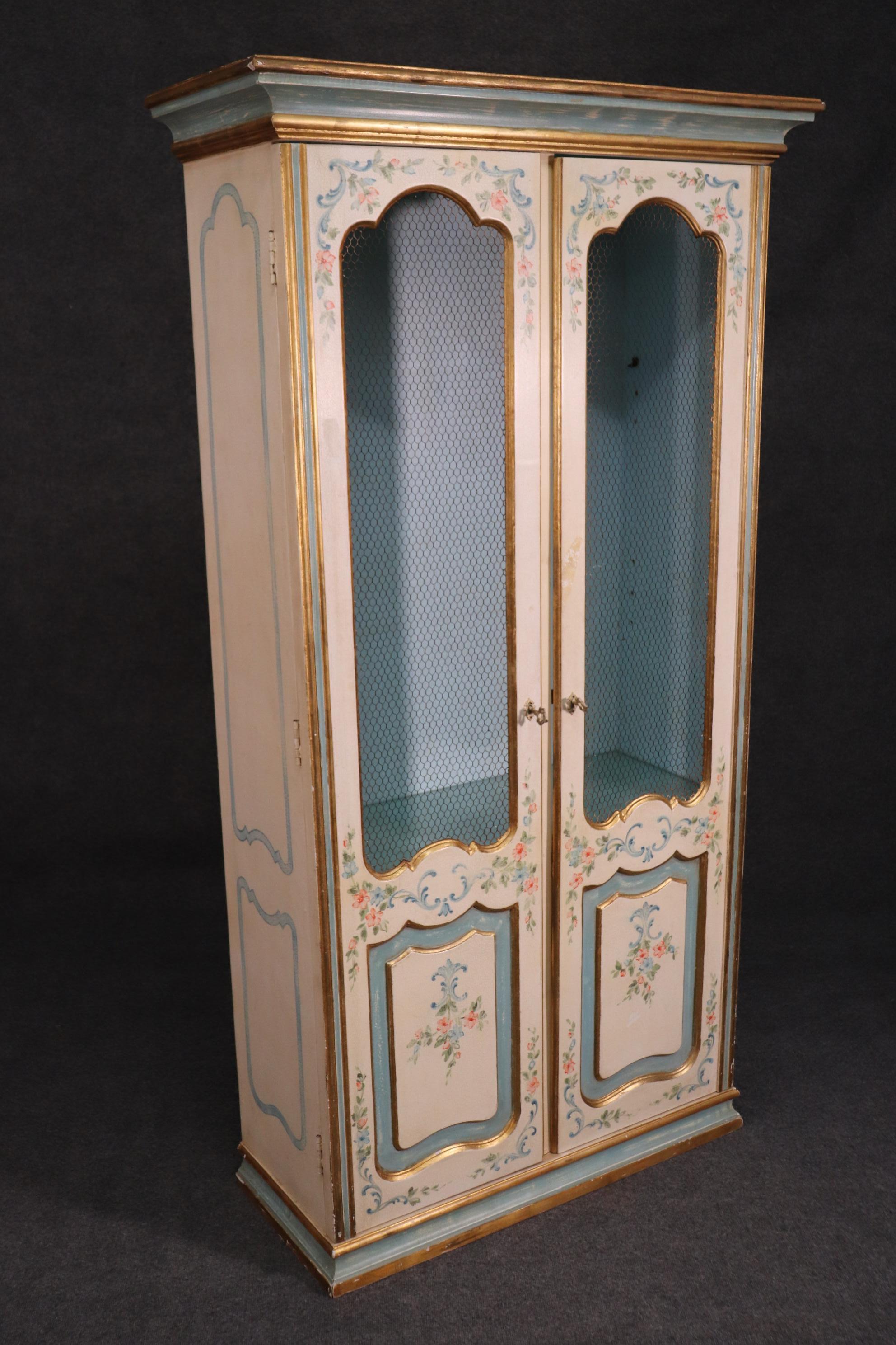 This is a beautiful paint decorated display cabinet with a mesh grill insert for a light and airy feel. The cabinet dates to the 1940s and is Italian. Measures: 76 tall x 41 wide x 17 deep.