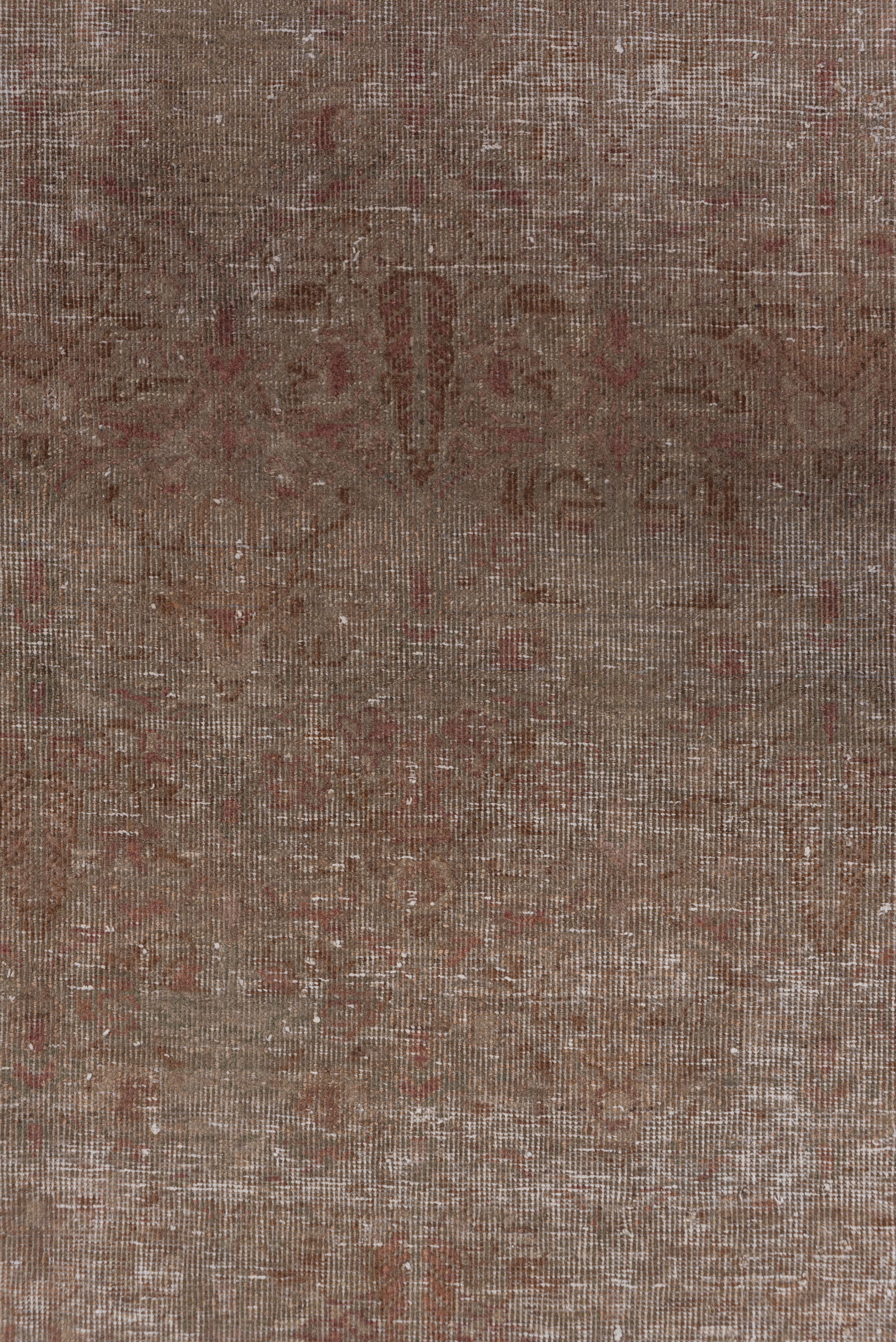 This distressed northern Indian town carpet shows a tone-one-tone small pattern of cypresses and palmettes within a close honeycomb lattice on a mauve-pink abrashed ground.