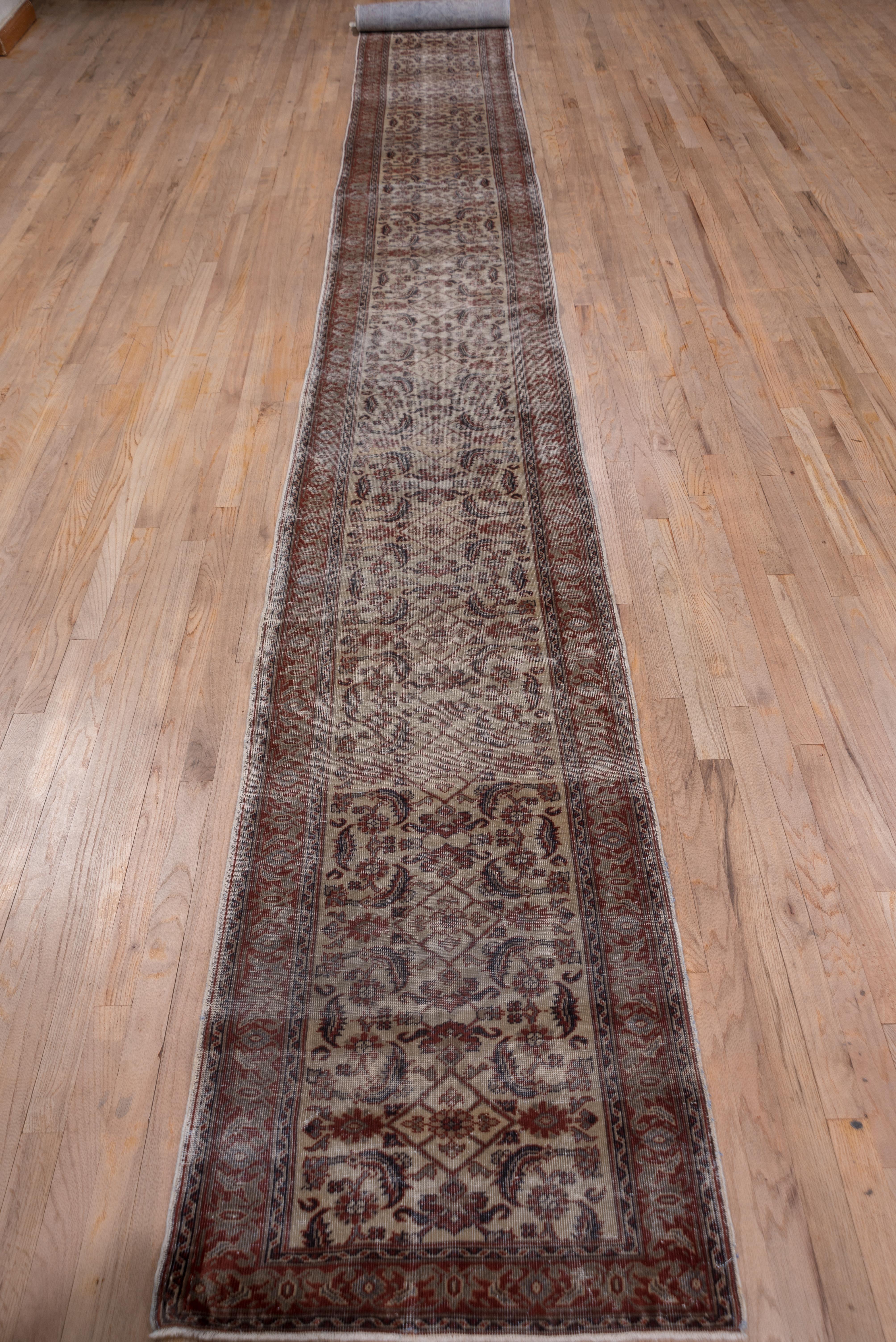 This rather distressed eastern Turkish sandy ivory ground narrow runner features a single column Persian Herati design with open diamonds, rosettes and 'fish' leaves. The brown border shows thick split leaves and geometric palmettes.