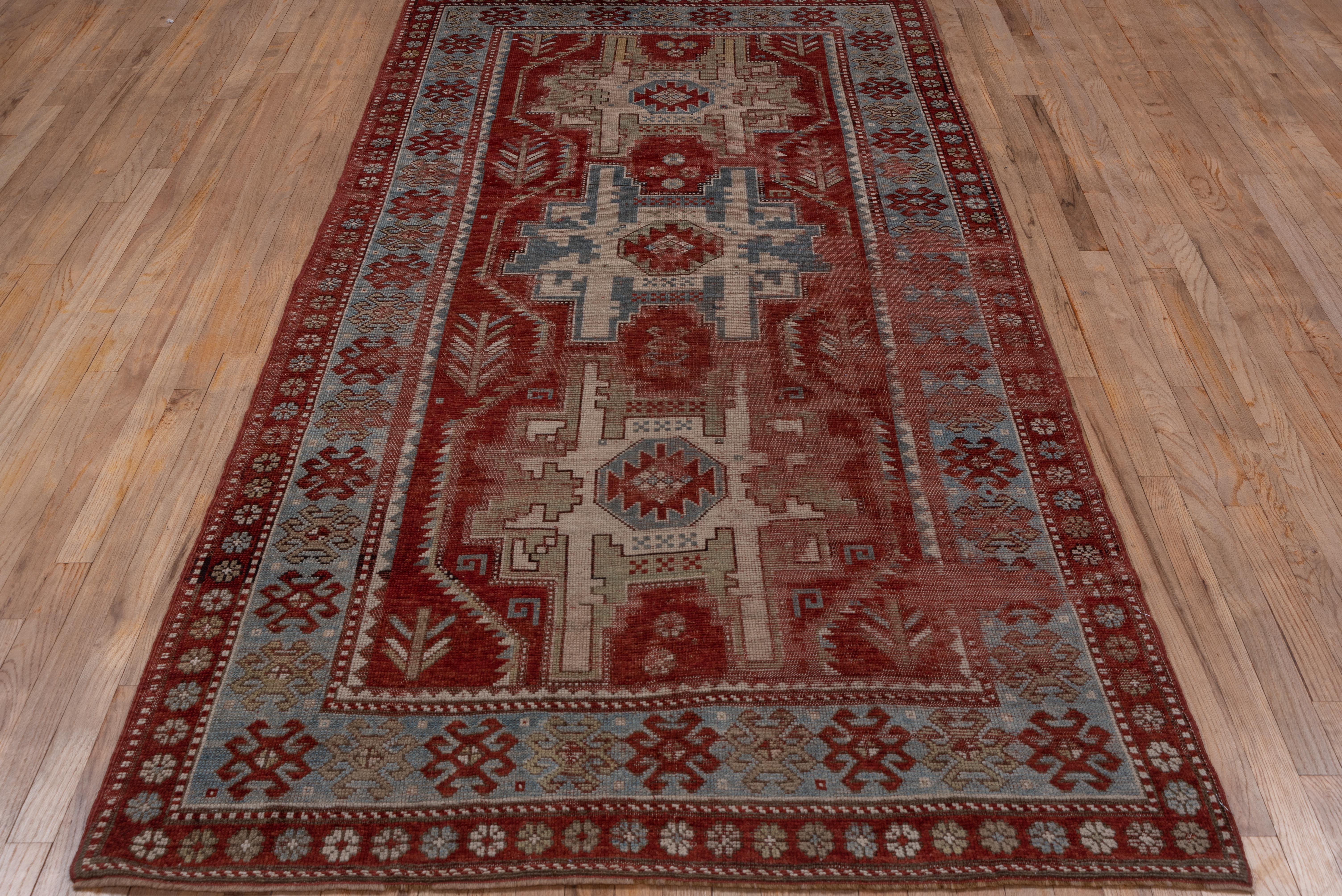 The madder red field displays three enormous Lesghi Stars with cream sub-stars and red ashik centres. The sky blue border of this South West Caucasian geometric rug show red and green hooked motive.