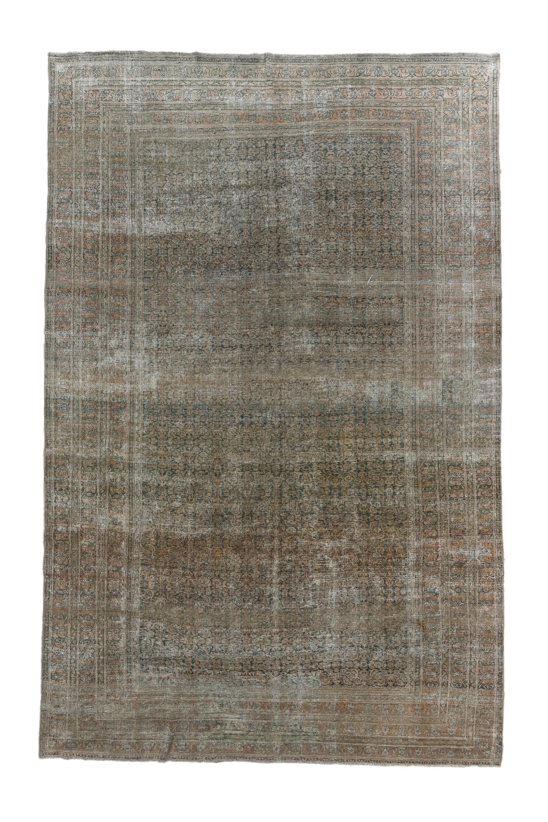 This linearly distressed city piece shows a compact allover Herati design on a slate field. The off white foundation visibly adds another allover tone. The three wide borders all show similar small botehs. Soft wool, cotton foundation. 

Rug