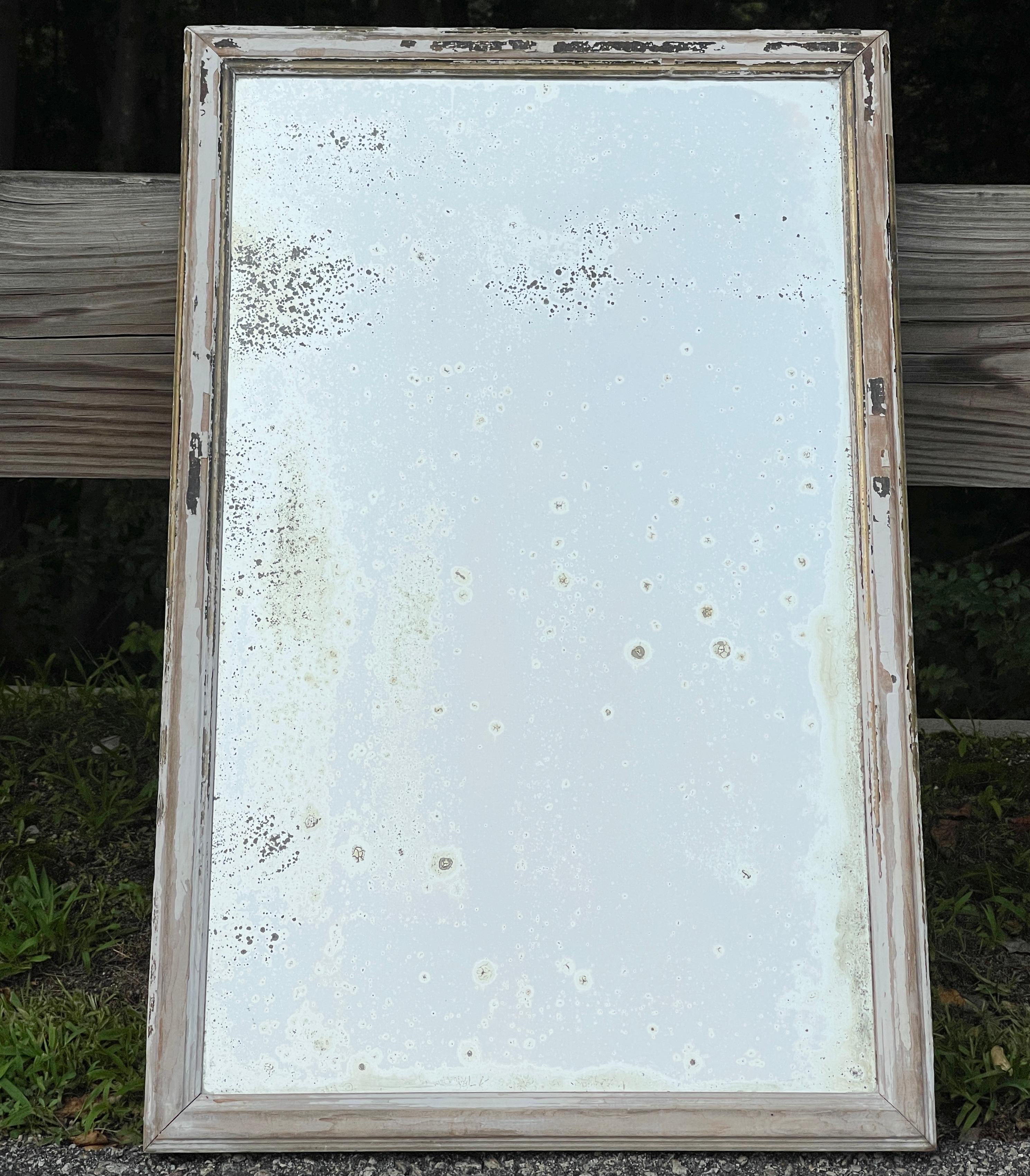 Very attractively distressed old mirror in a distressed old wood frame with traces of old paint.