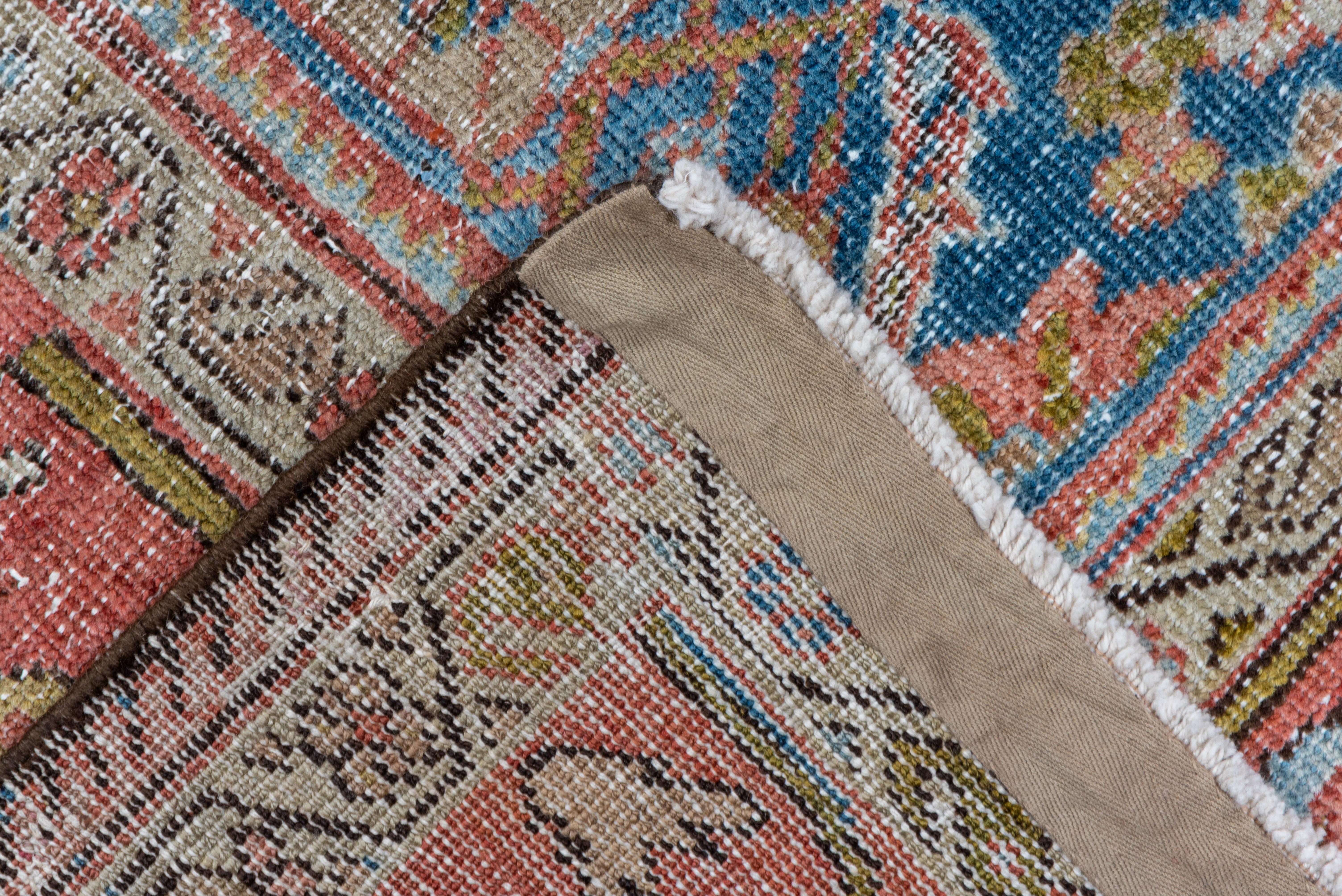 This rather distressed west Persian village kellegi (long rug) shows an all-over rosette, 'dumb bell' cartouche, forked arabesque and stiff vinery pattern on a sapphire blue field with the off white of the foundation adding another, softening, tone.