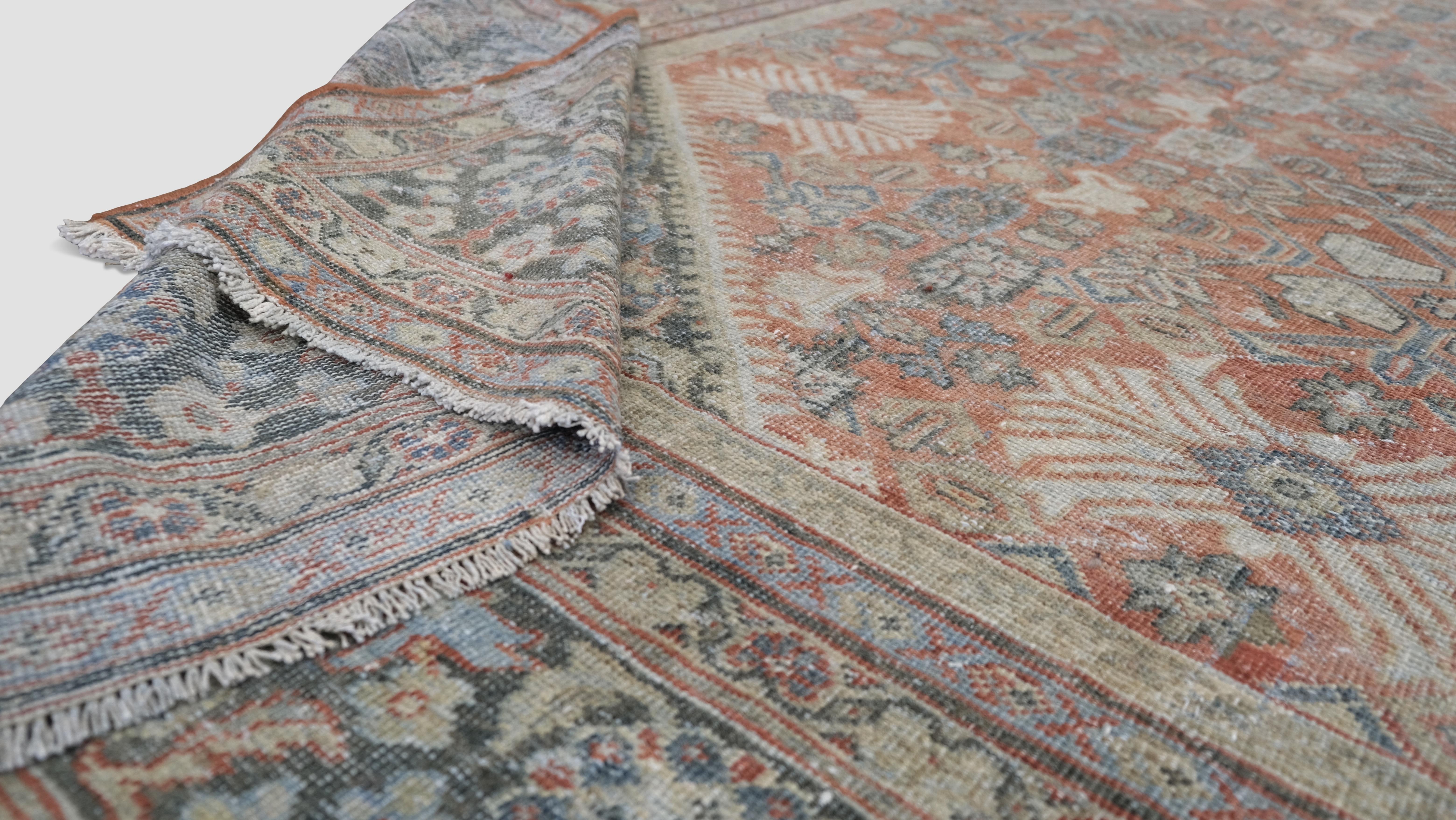 This antique Mahal piece showcases a vibrant design framed by intricate floral and geometric patterns in rich hues of rust, brown grey, and soft greens. Renowned for its durability and artistic detail, this rug is a masterpiece that blends