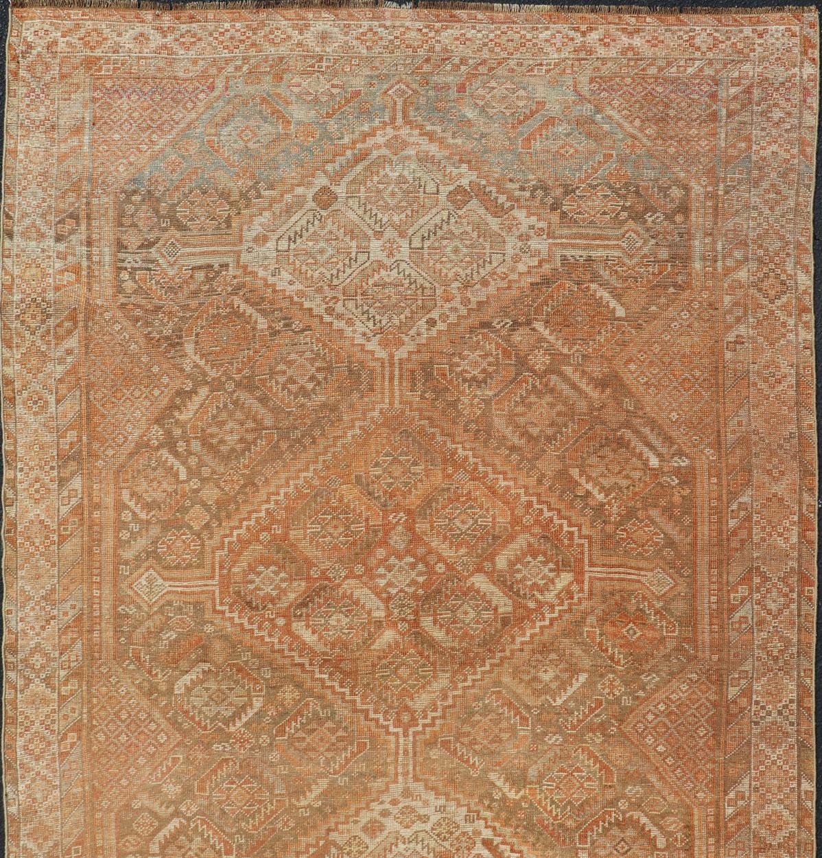 Persian antique Shiraz carpet in soft orange, light gray, light rust red and light brown with geometric medallions, rug EMB-8545-06, country of origin / type: Iran / Shiraz, circa 1920.

This antique distressed Persian Shiraz rug (circa early 20th