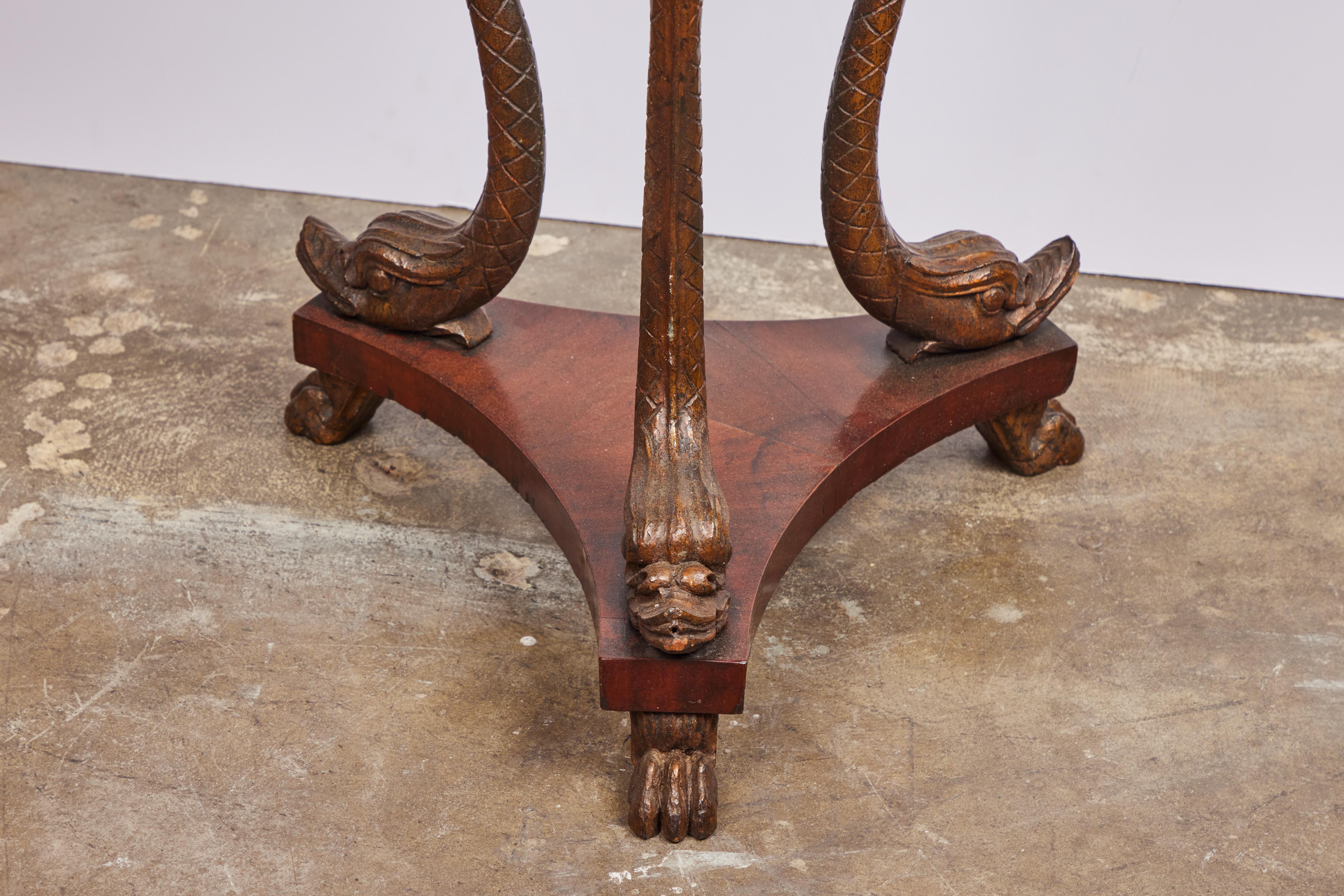 A wonderful, hand-carved, solid walnut, parcel ebonized, veneered Venetian three leg side table inset with later marble top in the grotto style. The three dolphin form legs atop a raised base on paw feet.