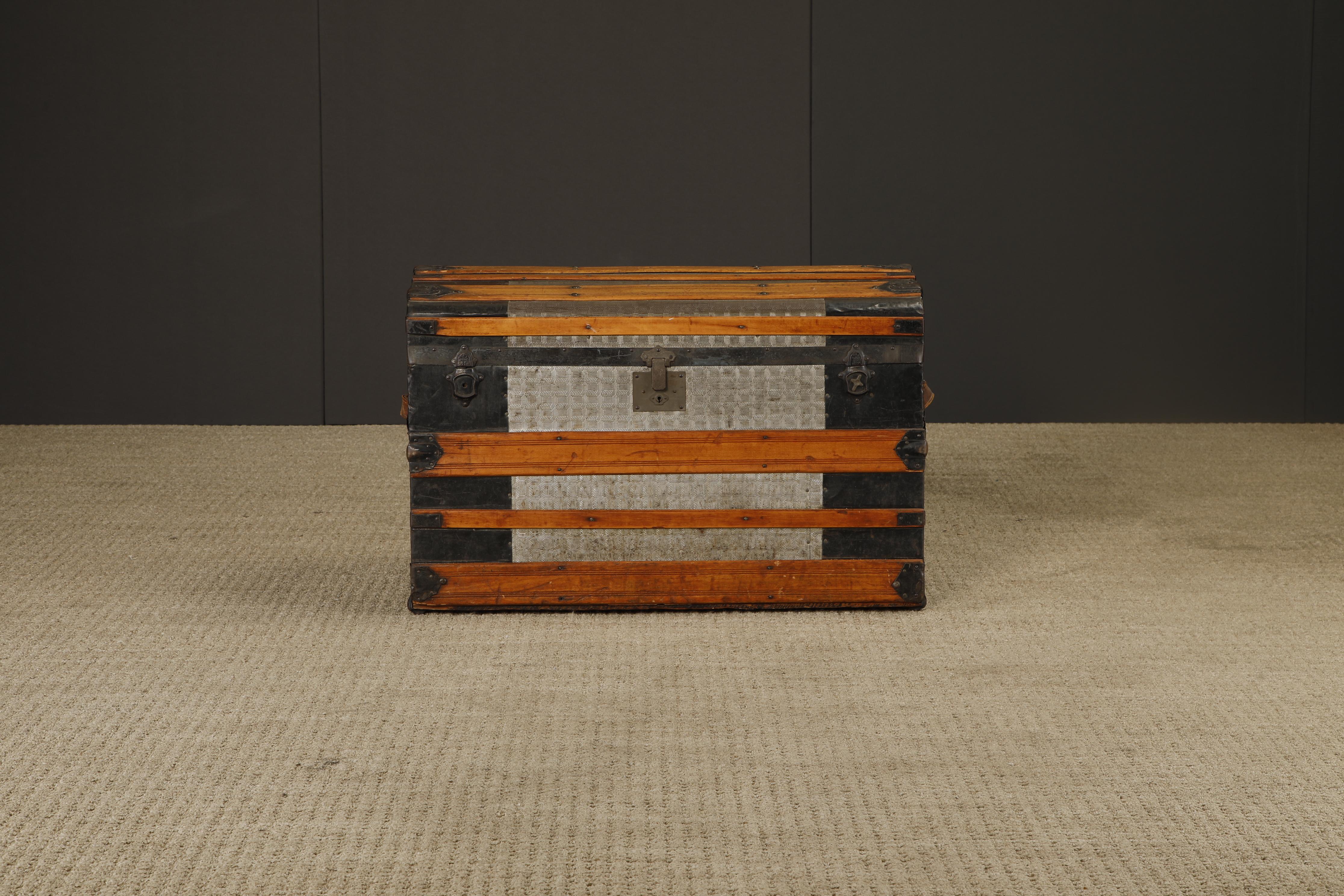 Exemple frappant de l'artisanat américain de la fin du XIXe siècle en matière de bagages, cette malle à vapeur antique présente des panneaux en zinc gaufré associés à de larges lattes de bois, des cerclages en métal noir et des ferrures authentiques